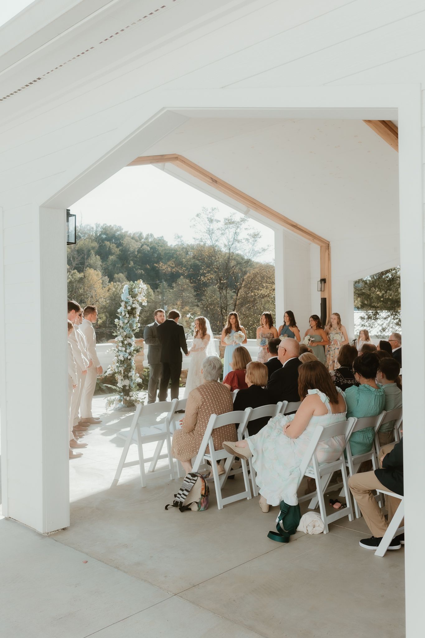Wedding guests seated under an elegant white pavilion during ceremony.