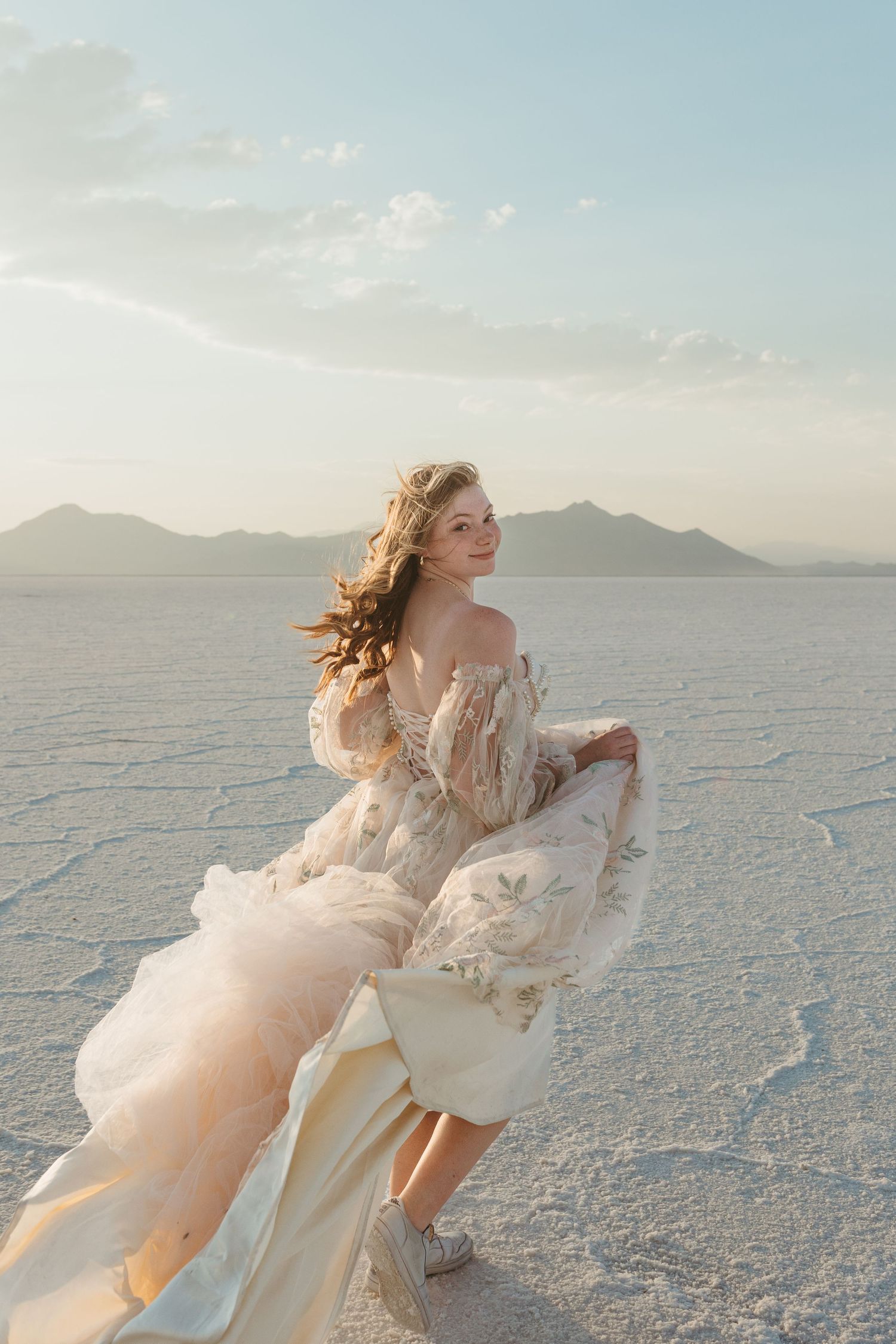 Ethereal bridal portraits in flowing white dress on salt flats at sunset.