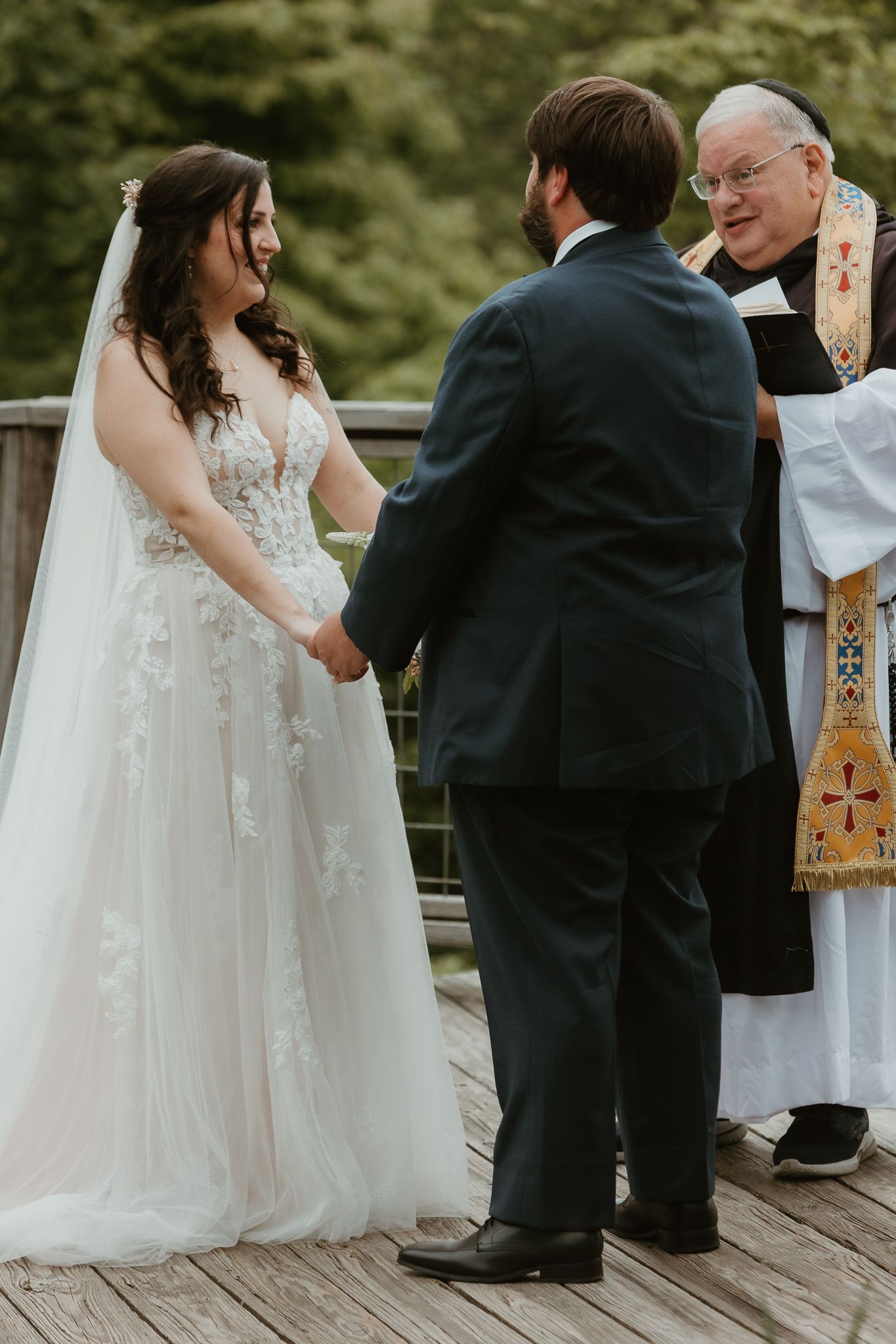 Wedding ceremony moments on wooden deck with mountain backdrop.