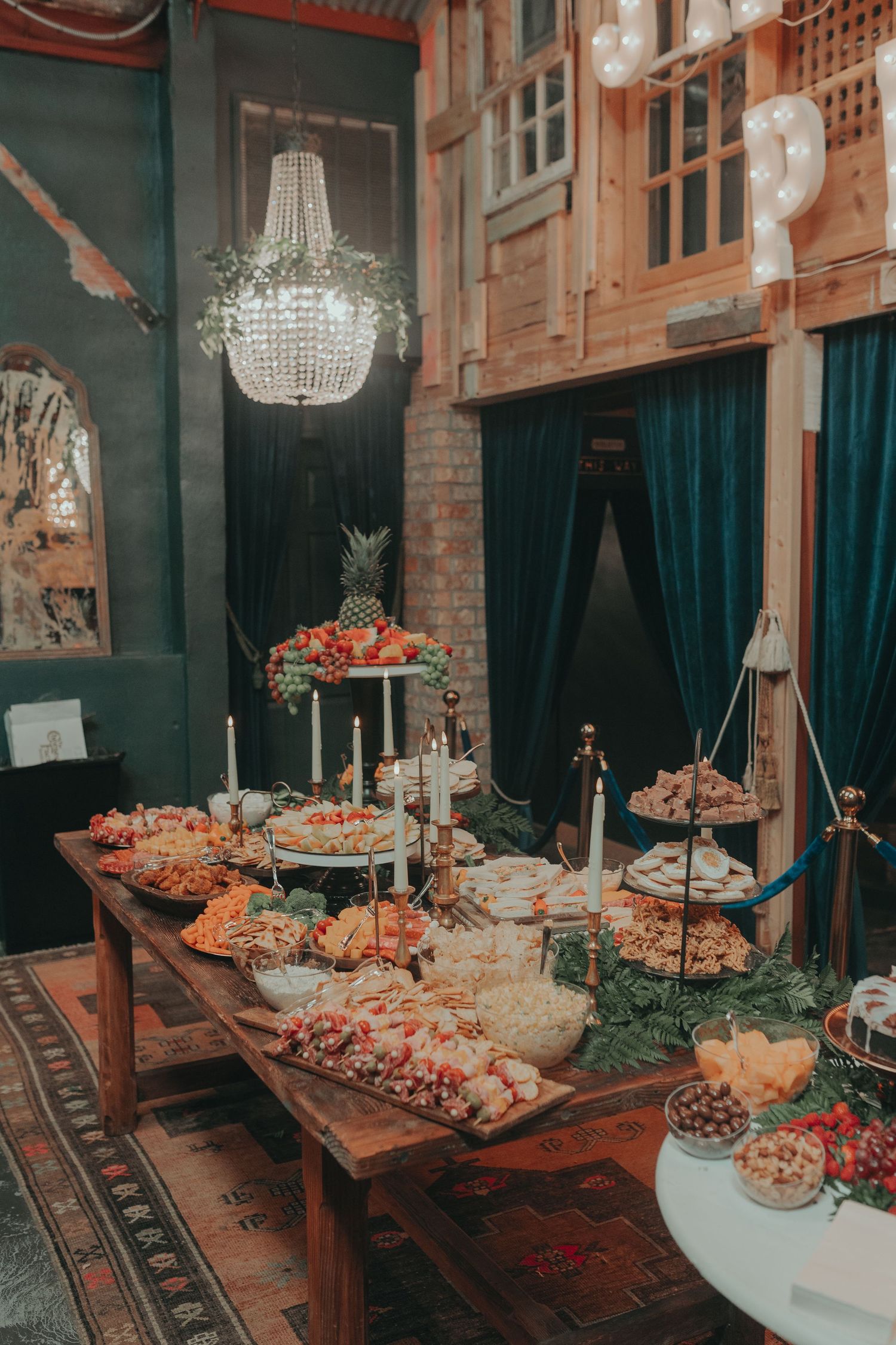 Elegant wedding reception table with crystal chandelier and abundant food displays.
