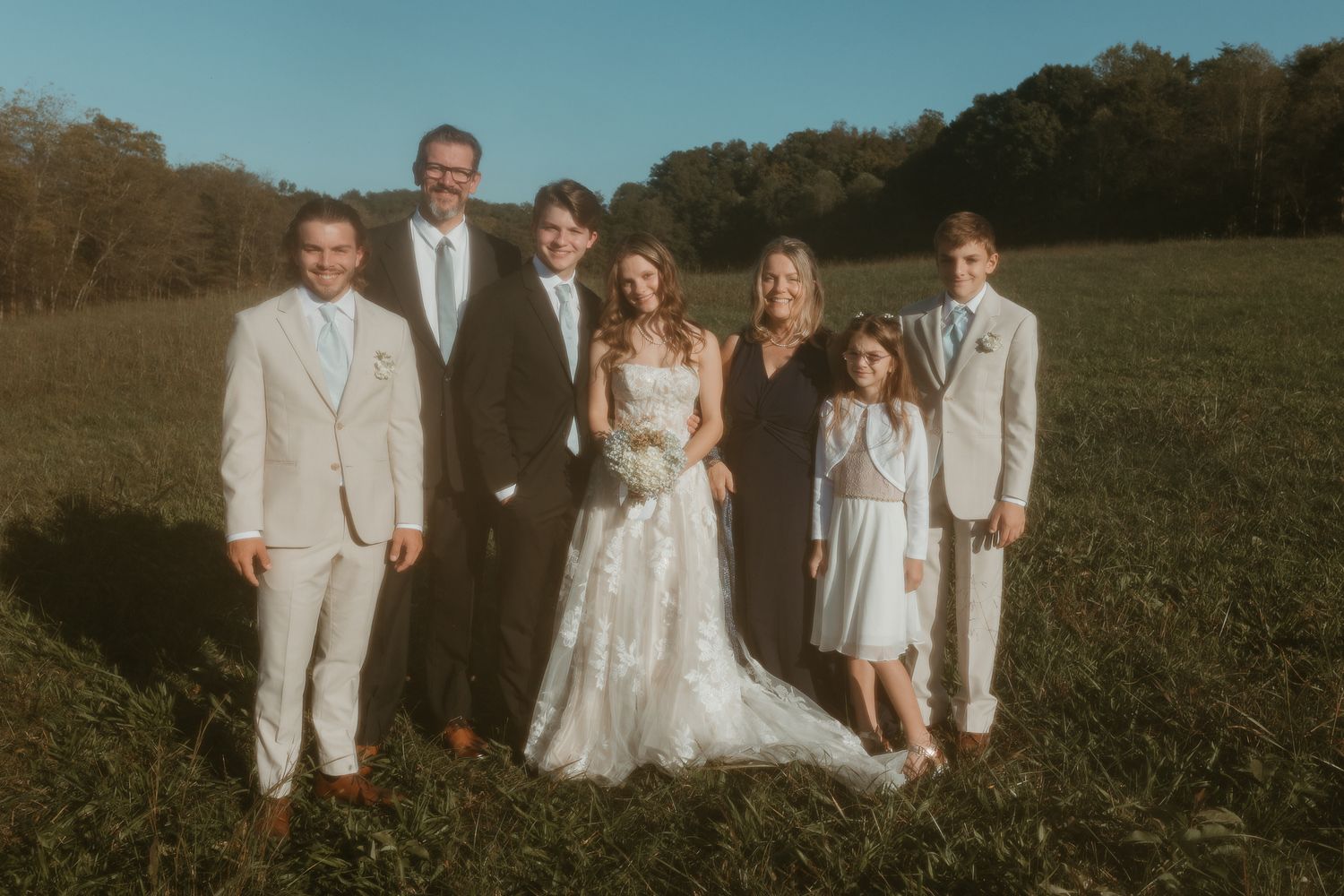 Wedding group portrait with bridesmaids and groomsmen in coordinated white outfits.