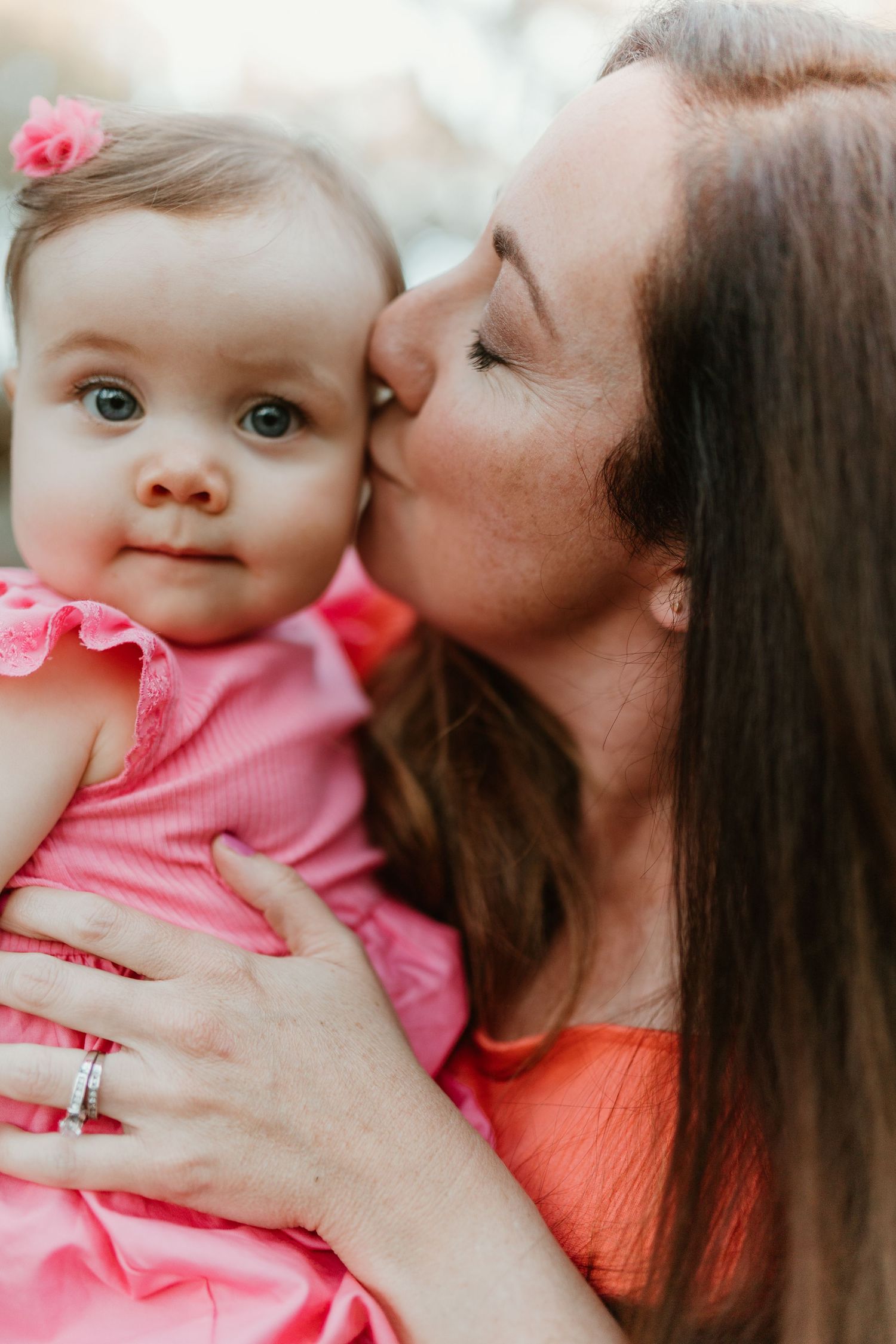 A tender moment captured between parent and baby wearing pink during an intimate portrait session.