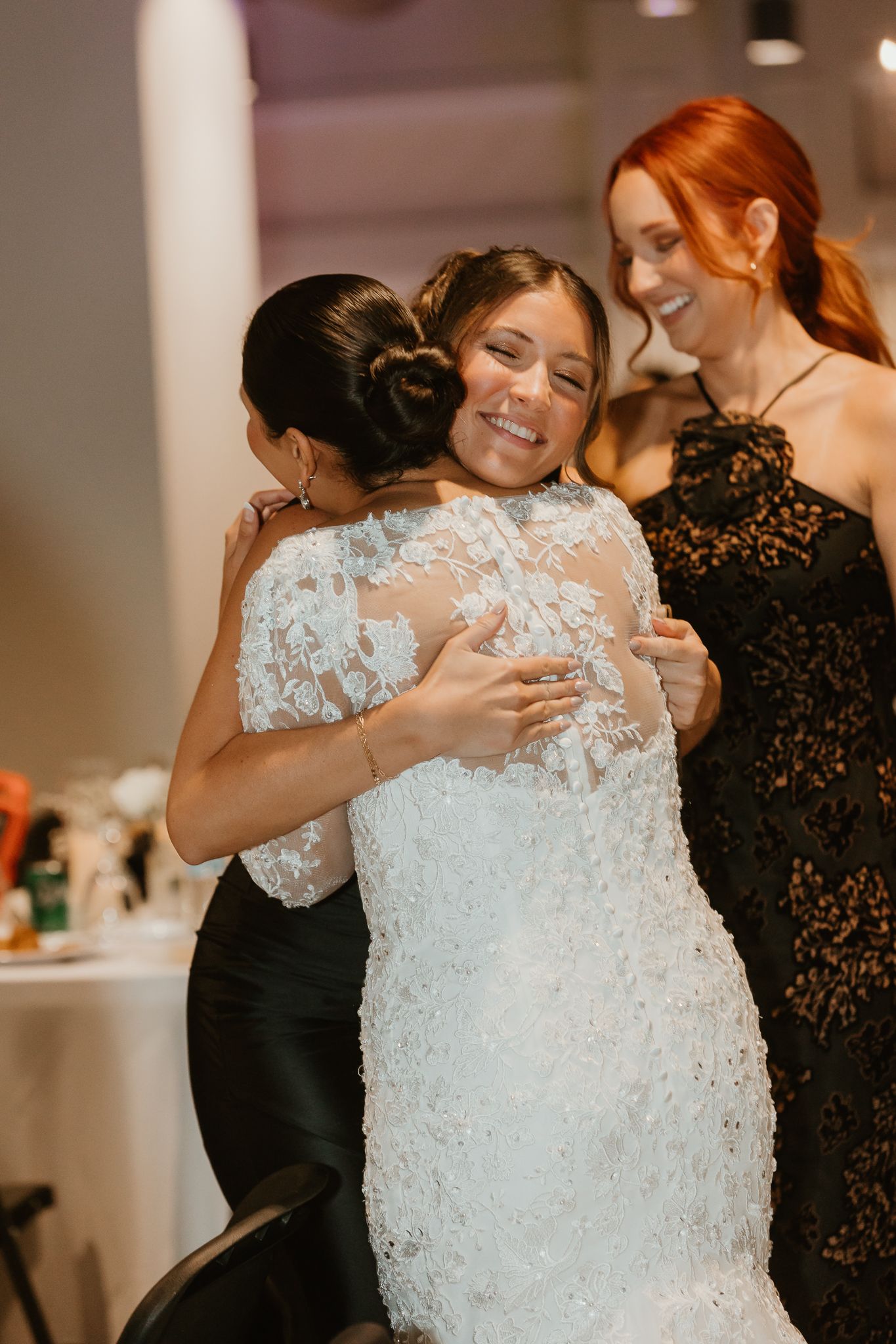 Wedding reception scene with guests embracing in formal attire.
