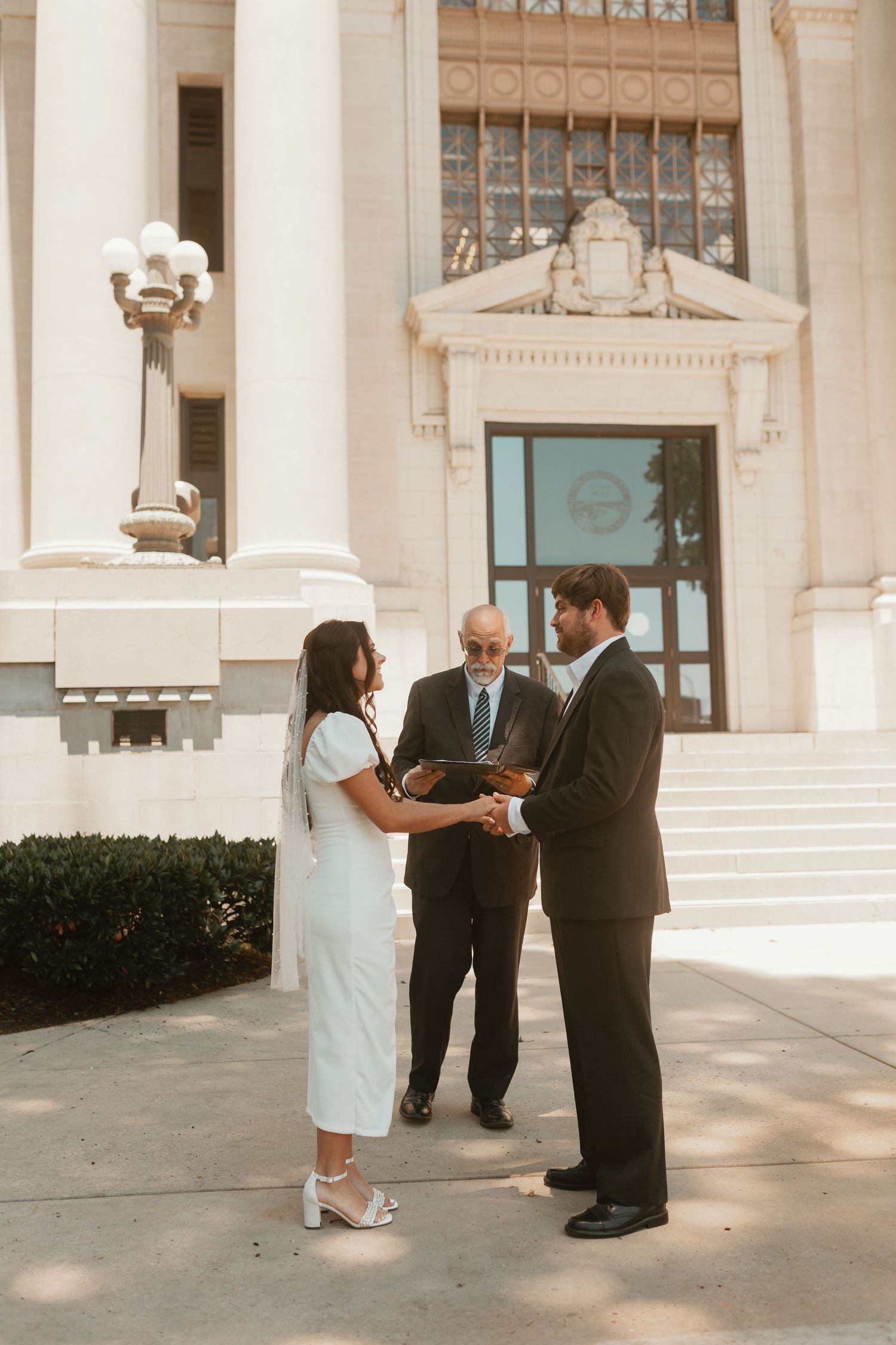 Wedding ceremony taking place on the steps of a grand government building with classical architecture.