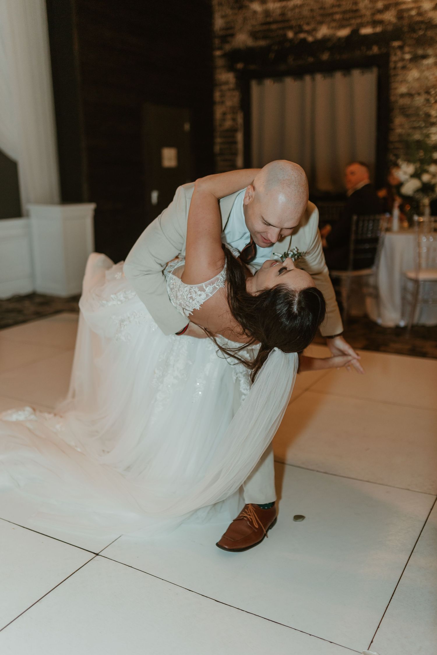 Romantic dip during wedding first dance on white dance floor.