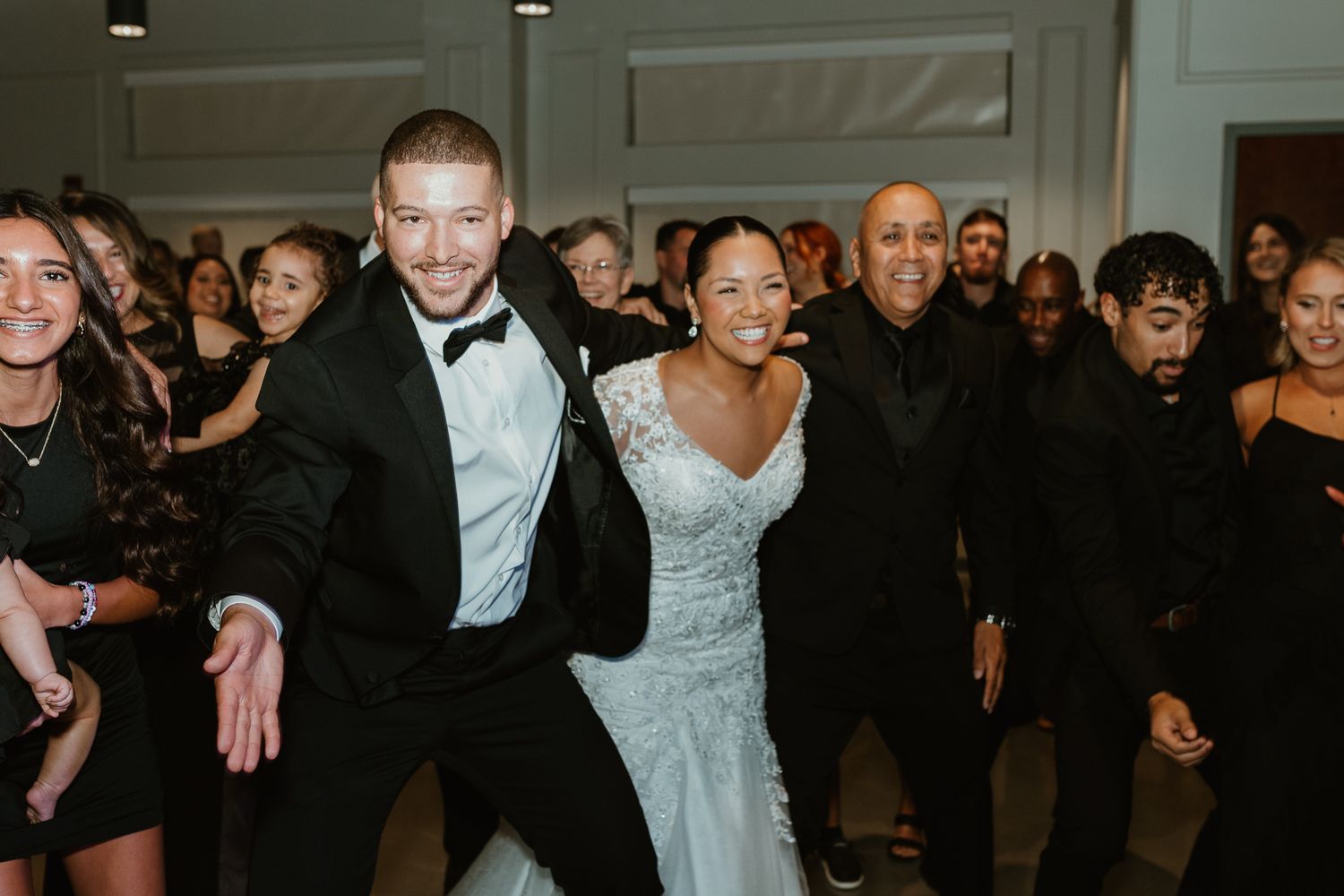 Wedding reception guests dancing and celebrating on a crowded dance floor.