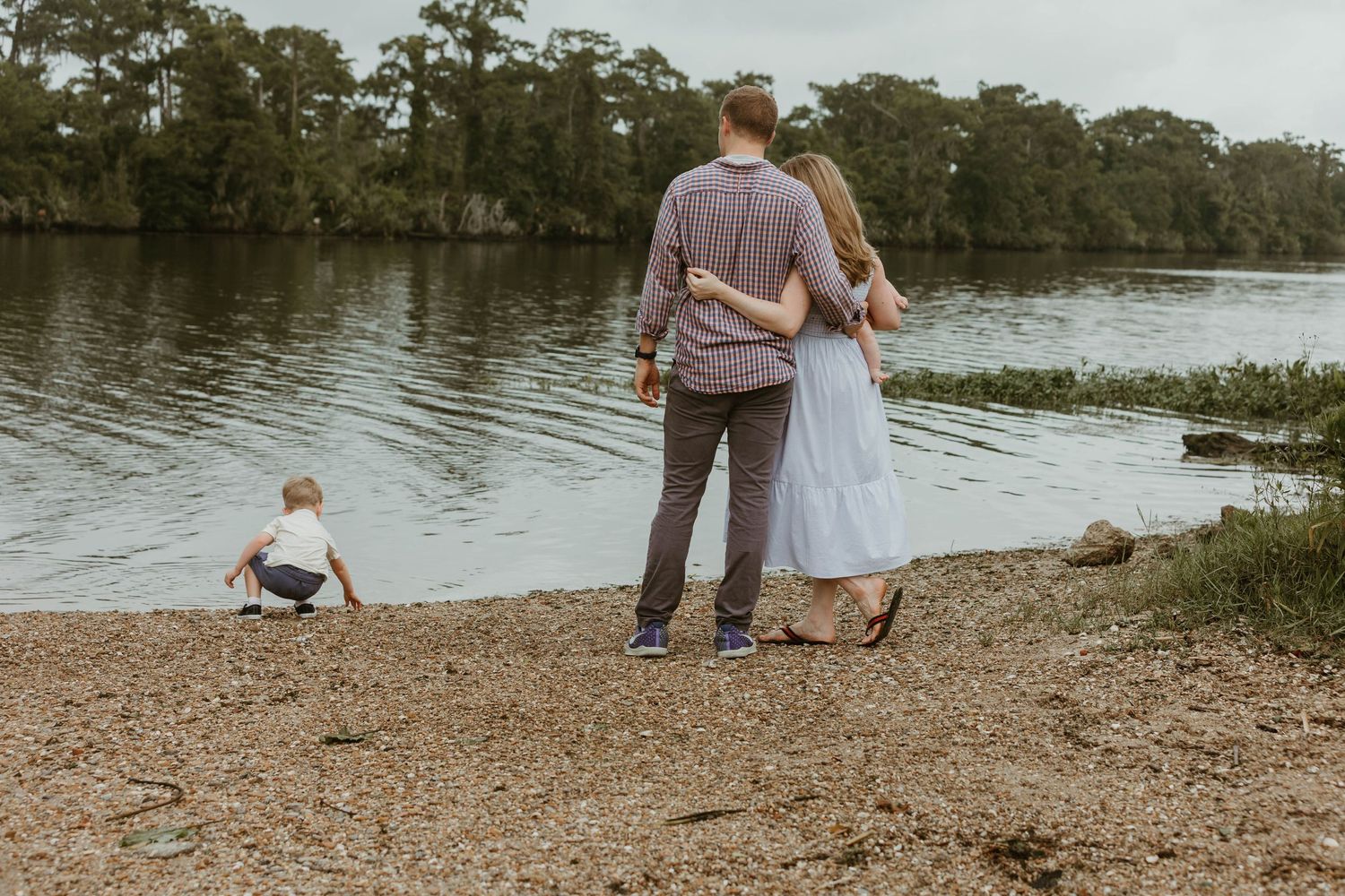 A serene family moment by the lake with child playing in background.