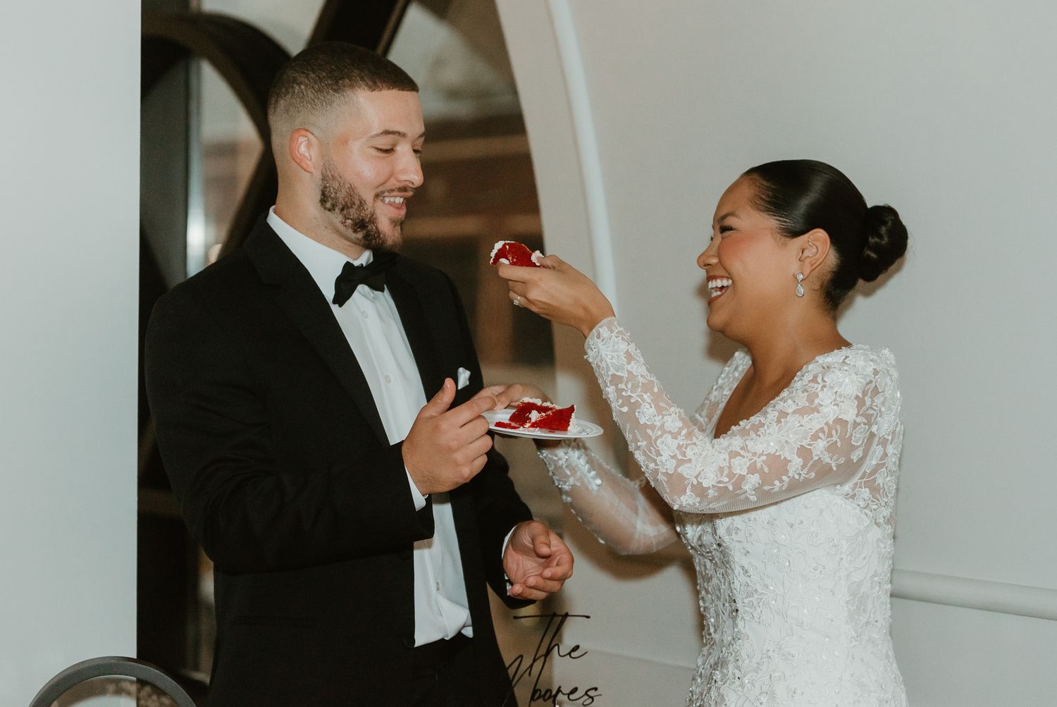Wedding celebration moment captured in an indoor setting with white walls.