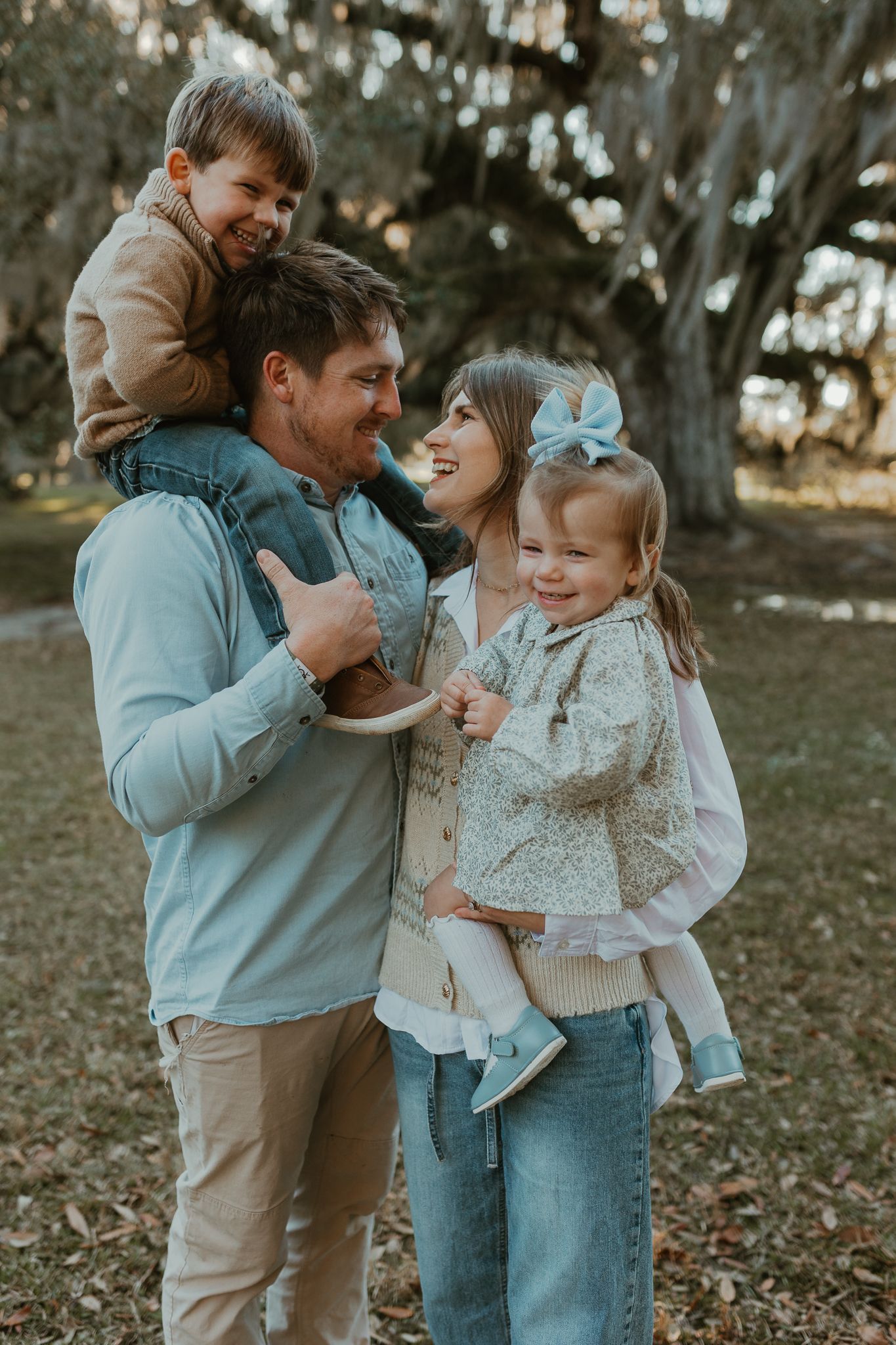 Loving family portrait in a park with casual attire and natural autumn lighting.
