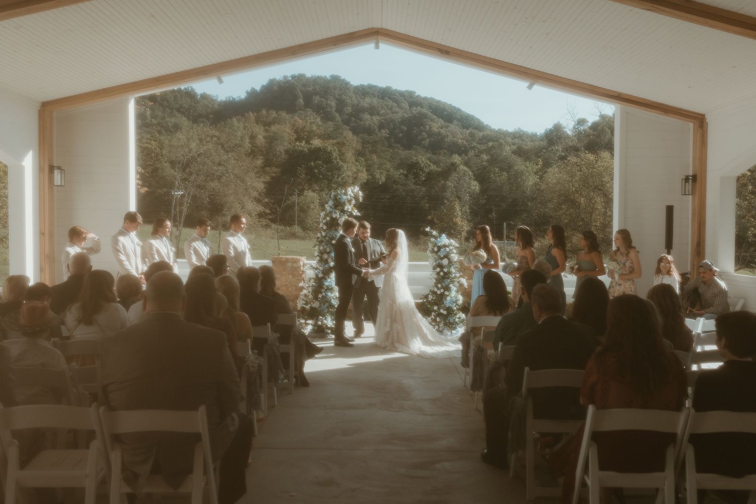 Panoramic view of wedding ceremony setup under white pillared structure.