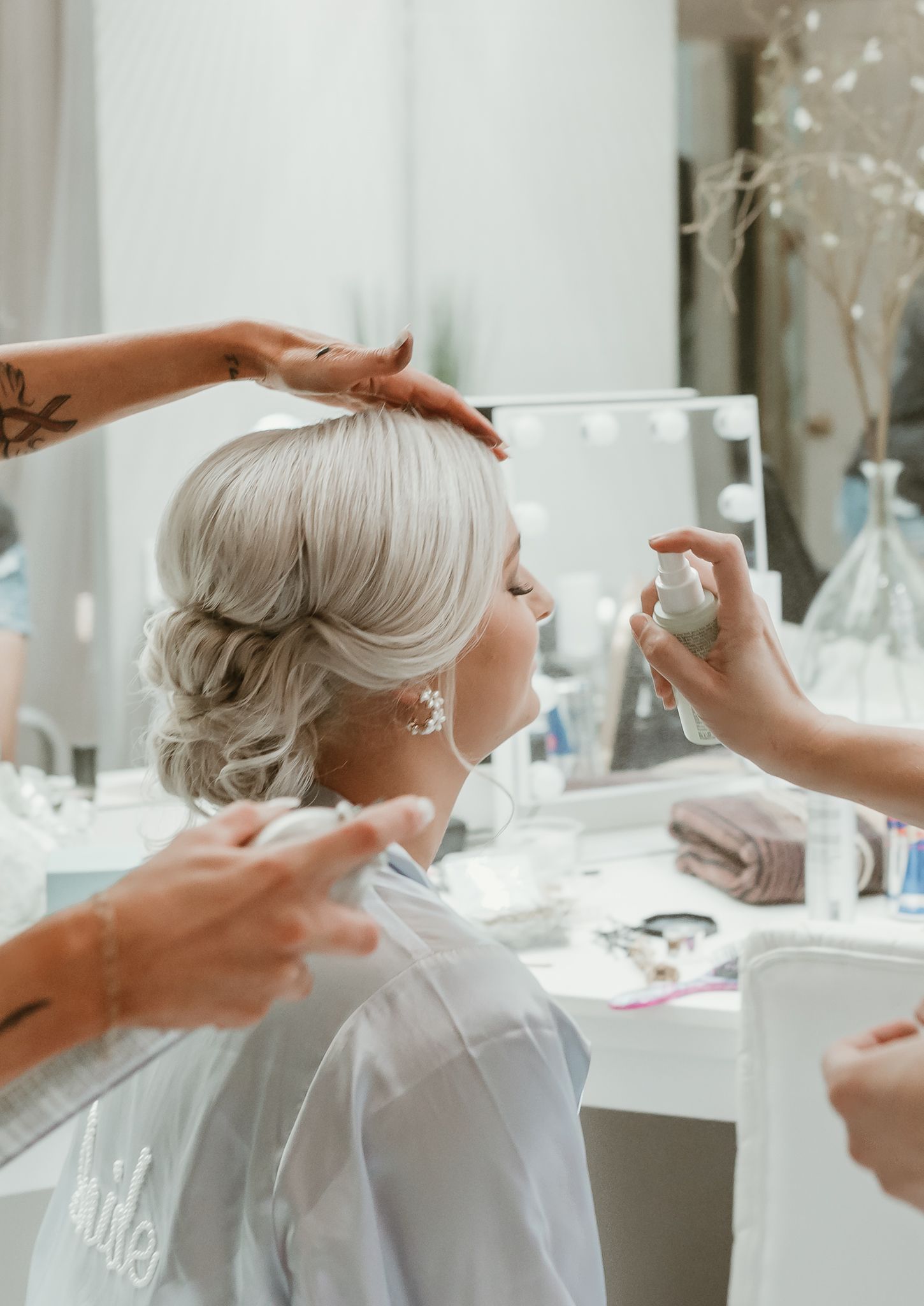 Hair styling preparation in bright white salon with multiple mirrors.