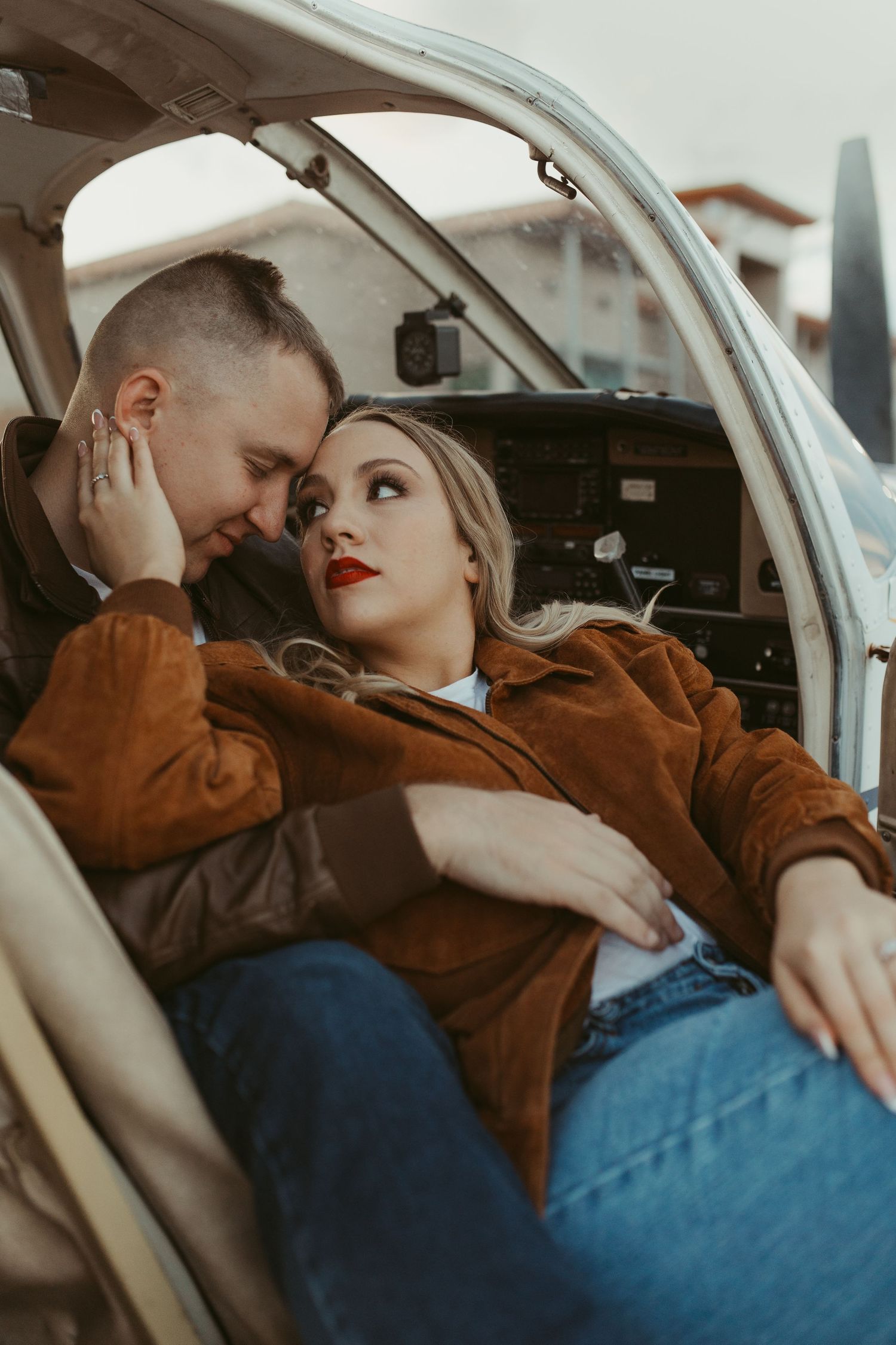 Couple in casual attire sharing an intimate moment inside a small aircraft cabin.