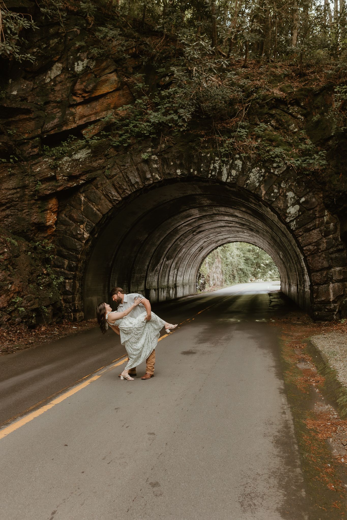 Romantic dance poses in a stone tunnel with natural lighting.