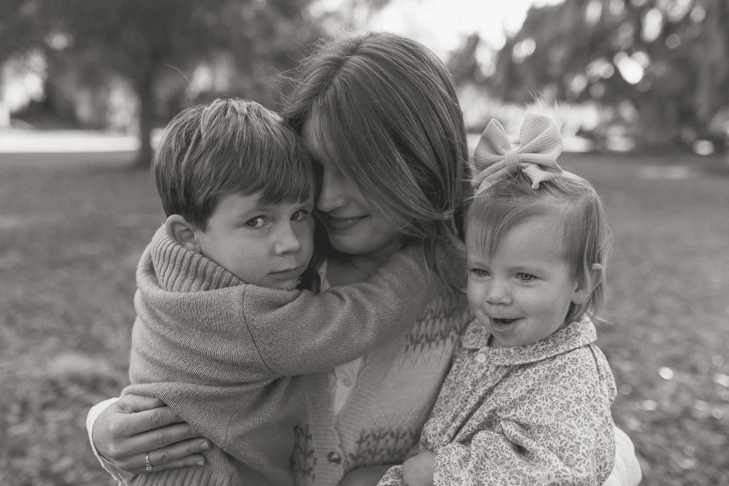 Series of intimate black and white photographs showing tender family moments in an outdoor setting.