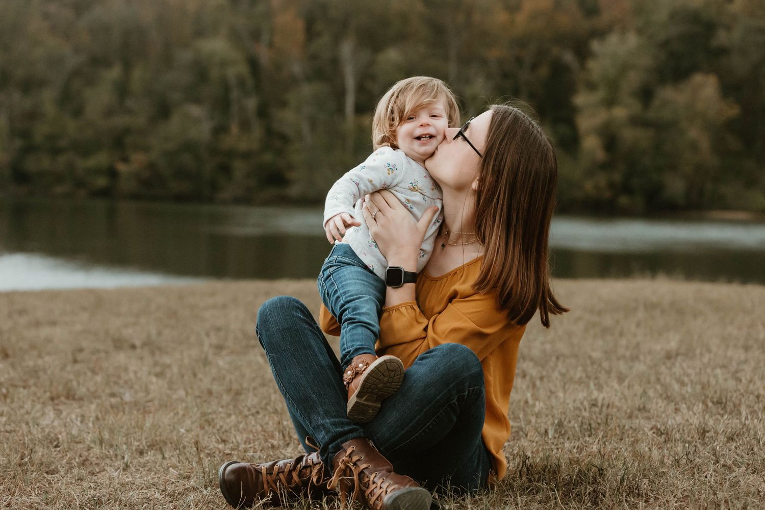 Family sharing tender moments together on a grassy hill during sunset.