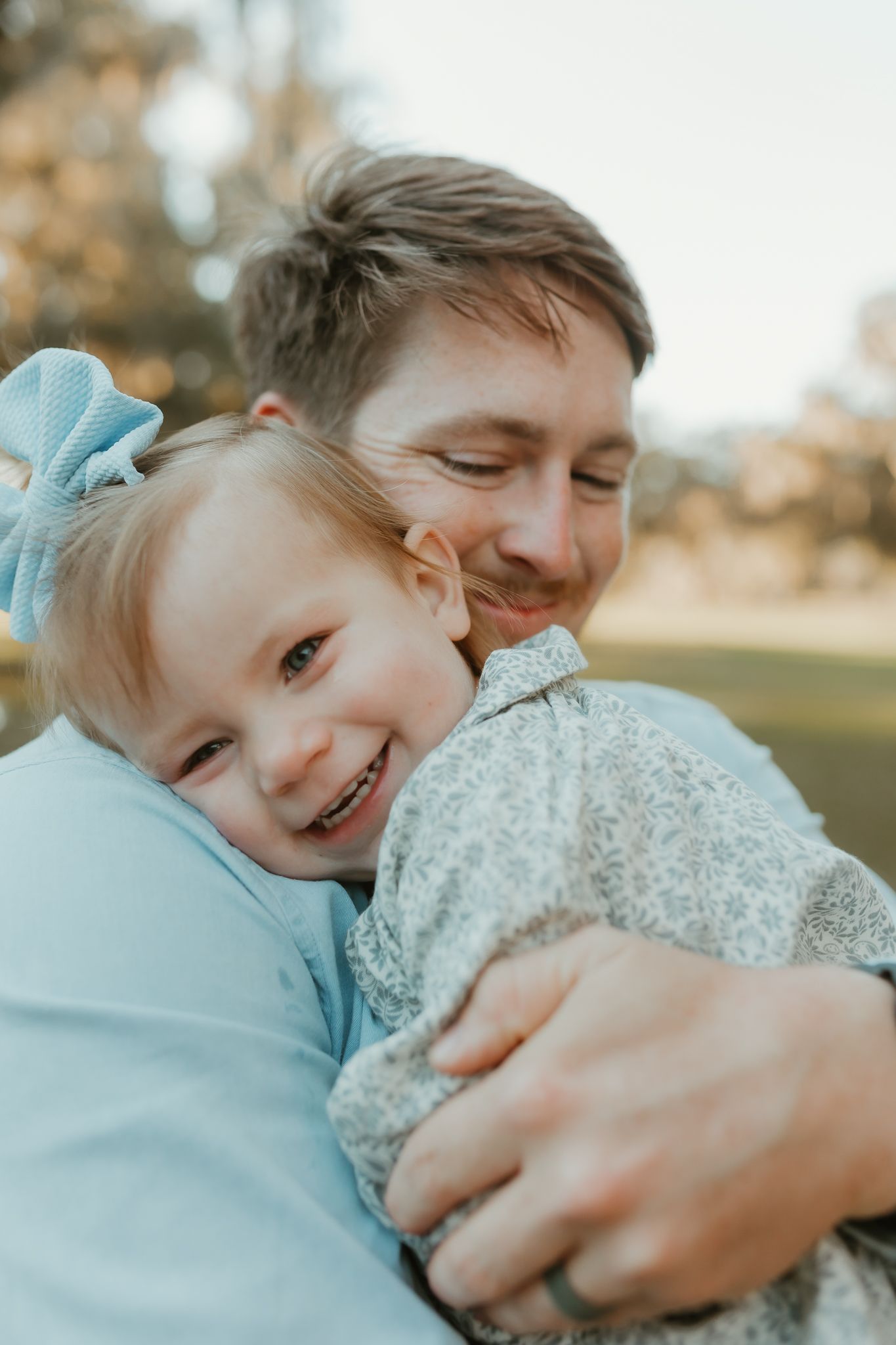 Joyful family sharing laughs and hugs in golden afternoon sunlight.