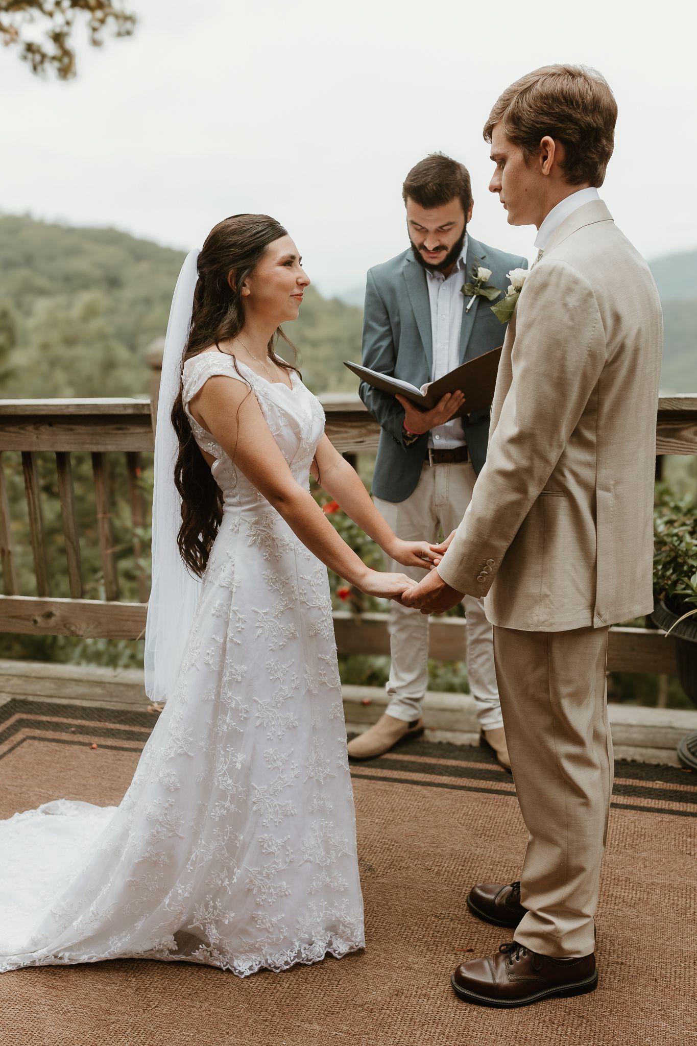 An intimate wedding ceremony taking place on a rustic wooden deck with mountain views.