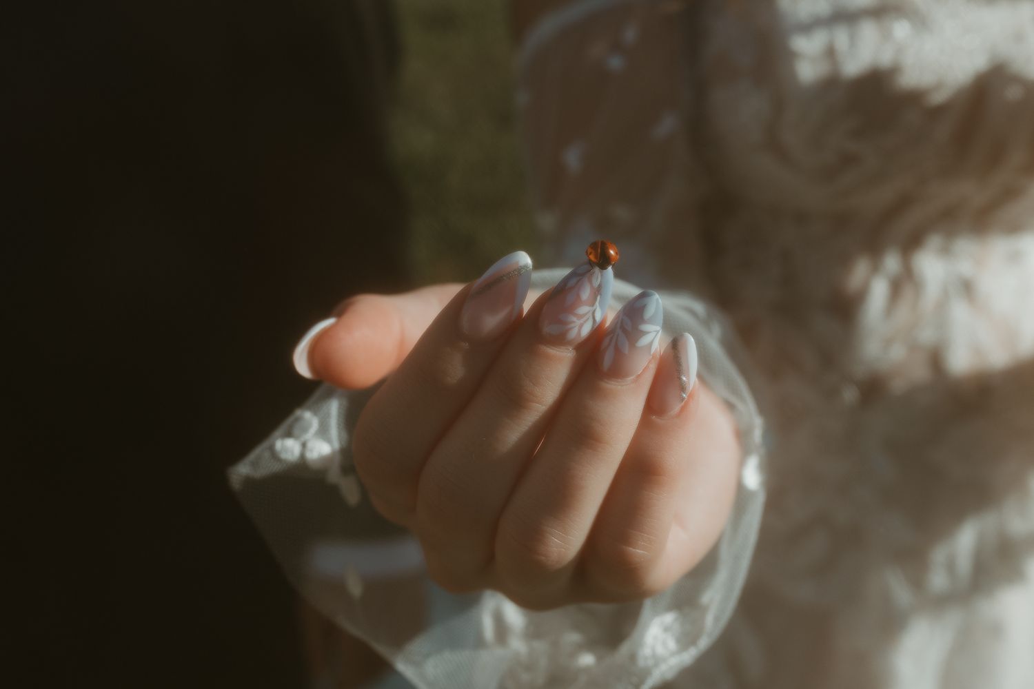 Close-up detail of intricate lace and beading on white wedding dress.