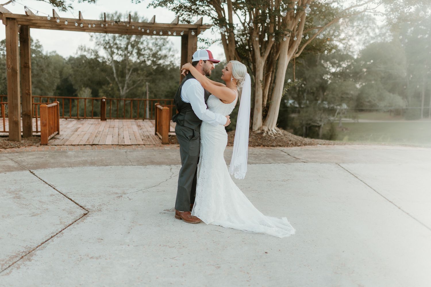 Wedding couple sharing romantic moments on a wooden deck surrounded by trees.