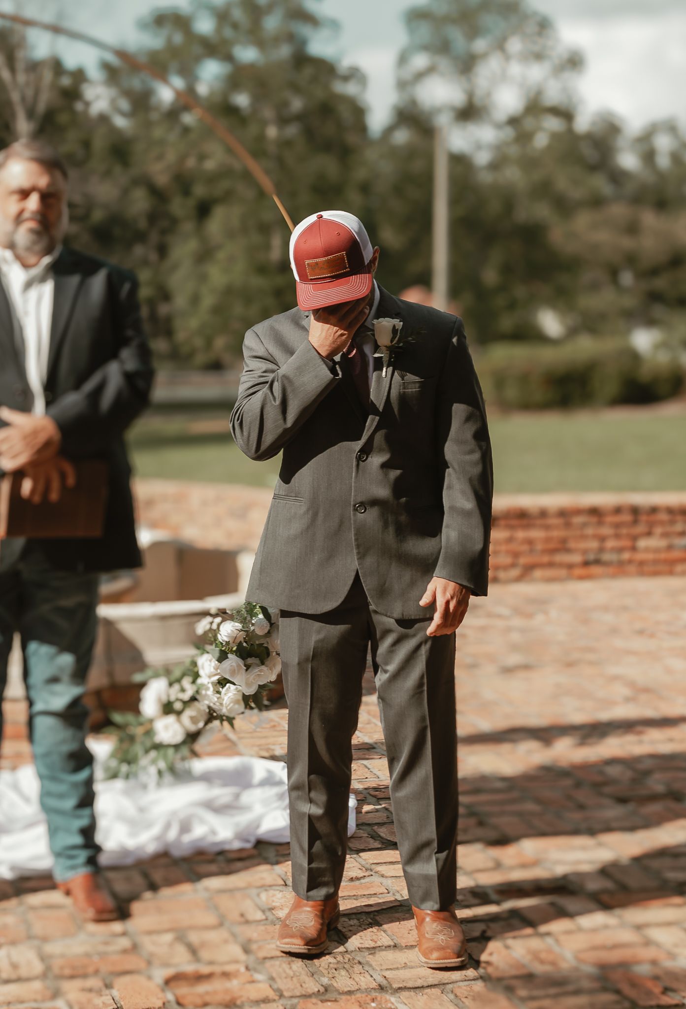 Wedding party members in formal attire standing on brick patio.