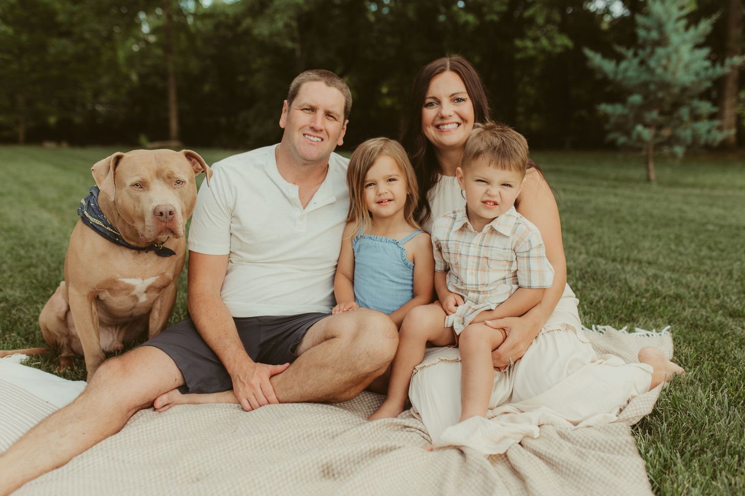 Family relaxing together on grass during an outdoor portrait session at golden hour.