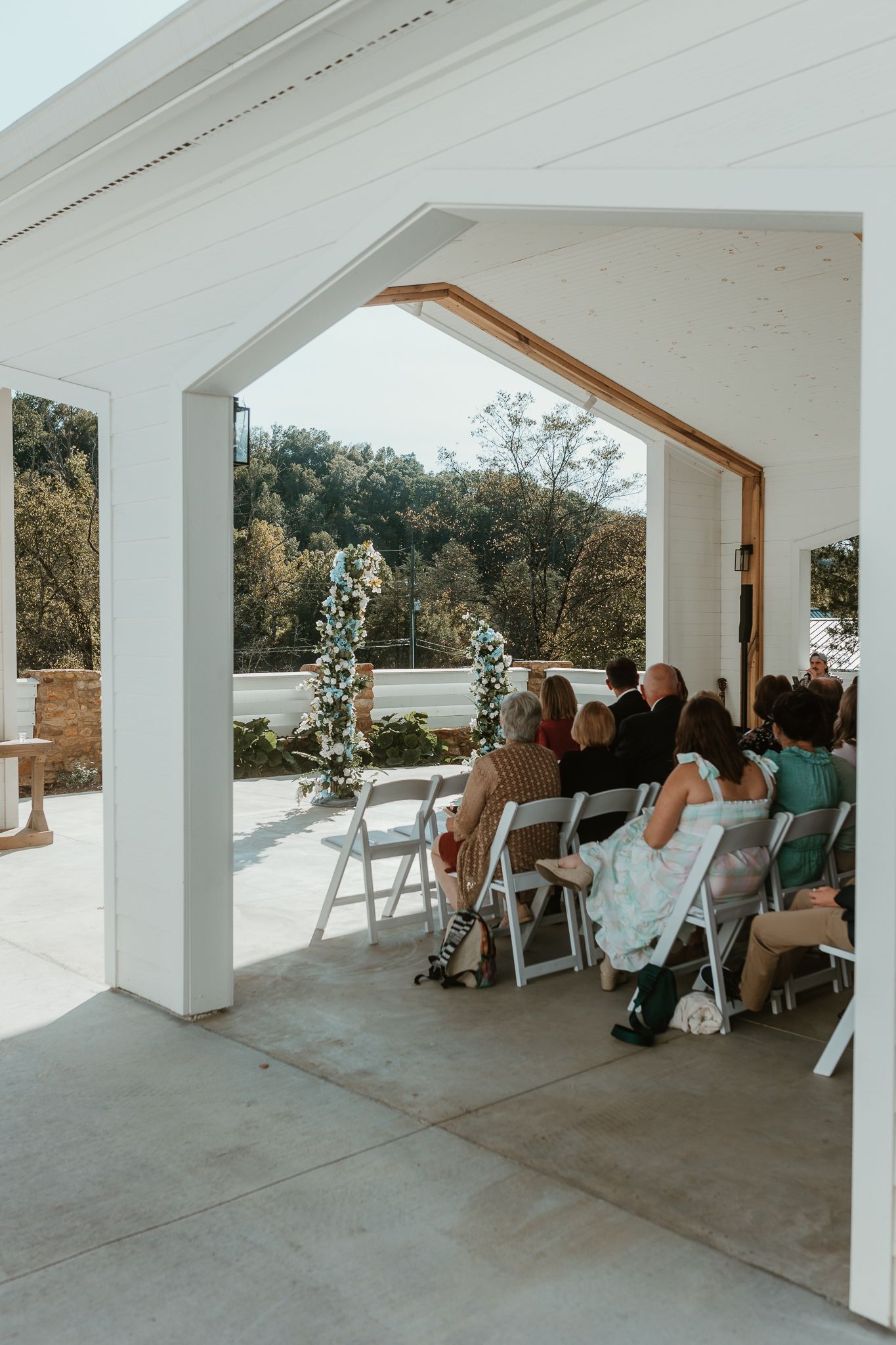 Outdoor covered wedding venue with white chairs and mountain backdrop.