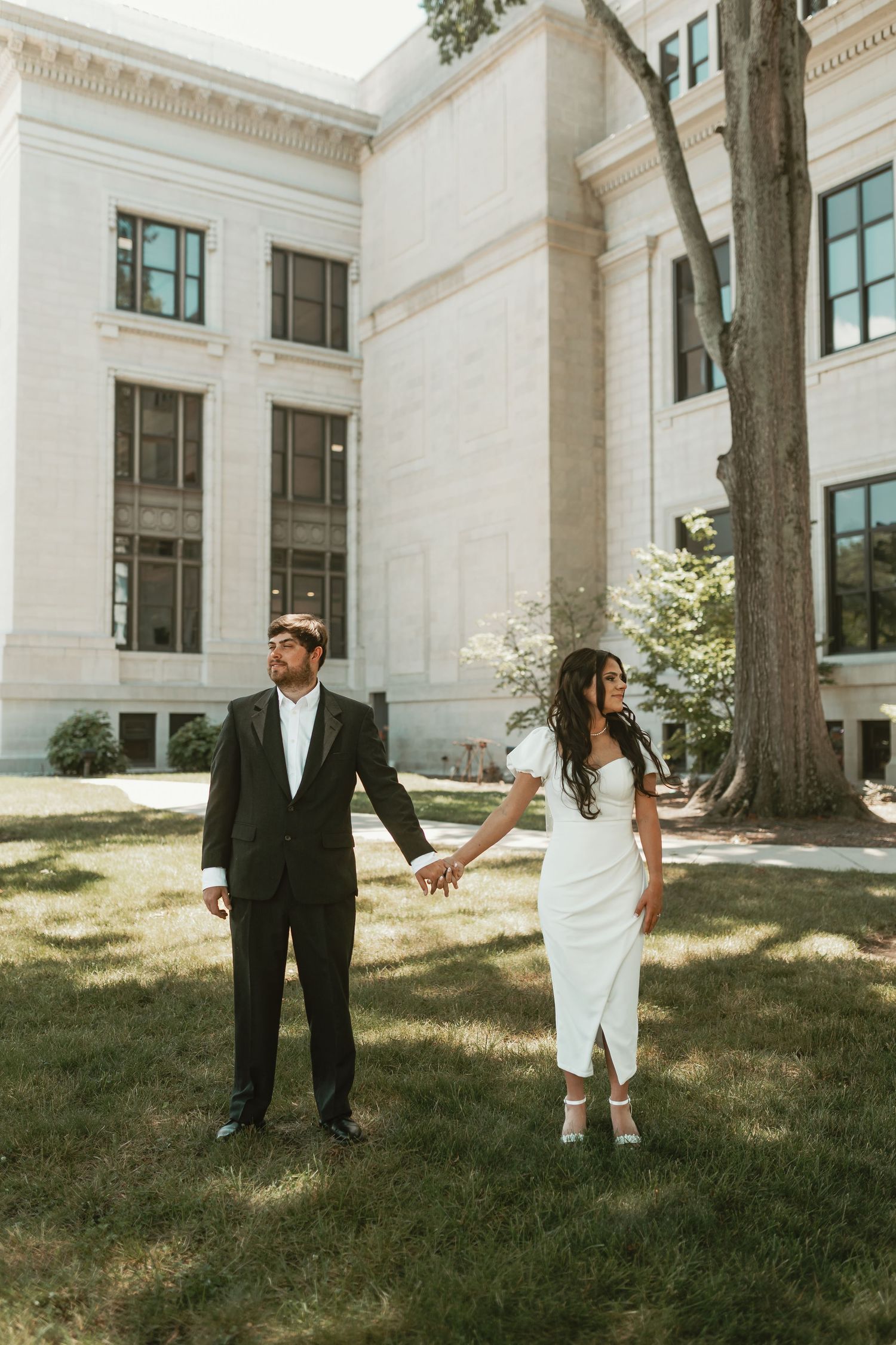 Newlyweds share candid moments on the lawn of a stately white building.