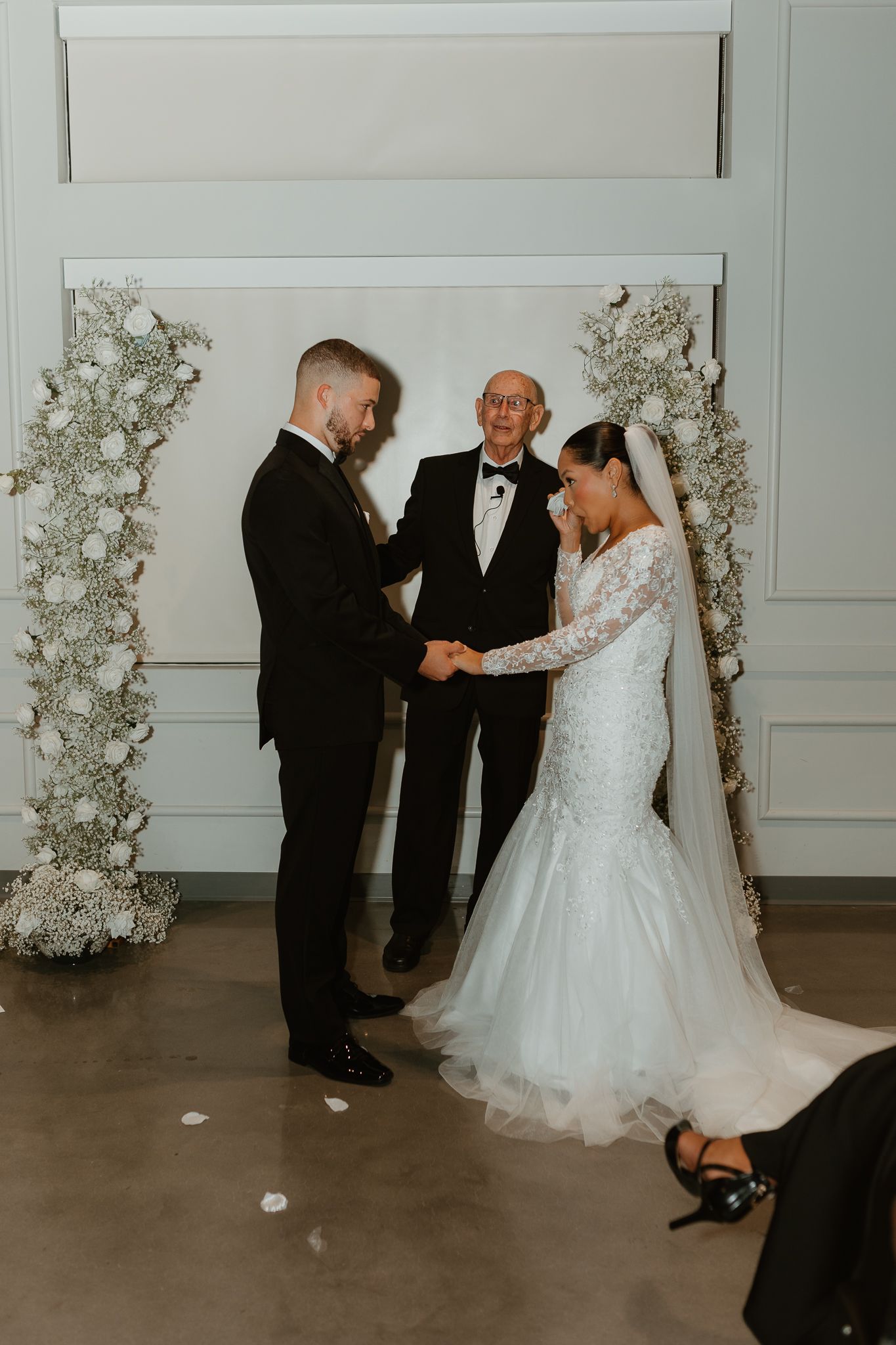 Wedding ceremony with white floral arrangements and elegant decor in a modern venue.