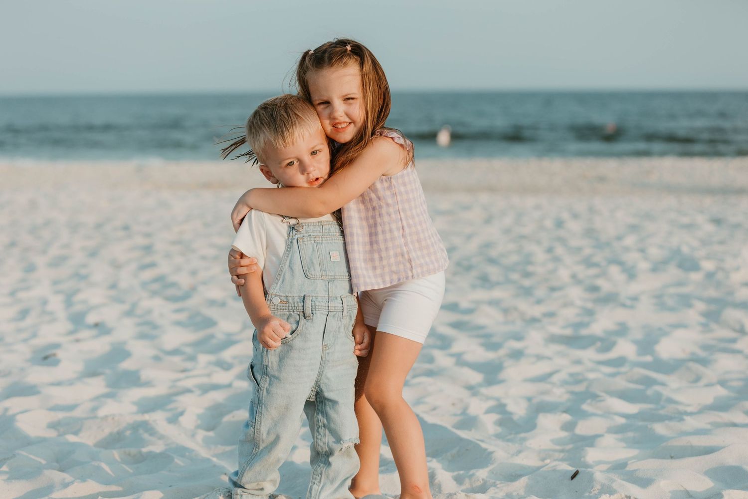 Family photoshoot series on a white sandy beach with soft lighting.