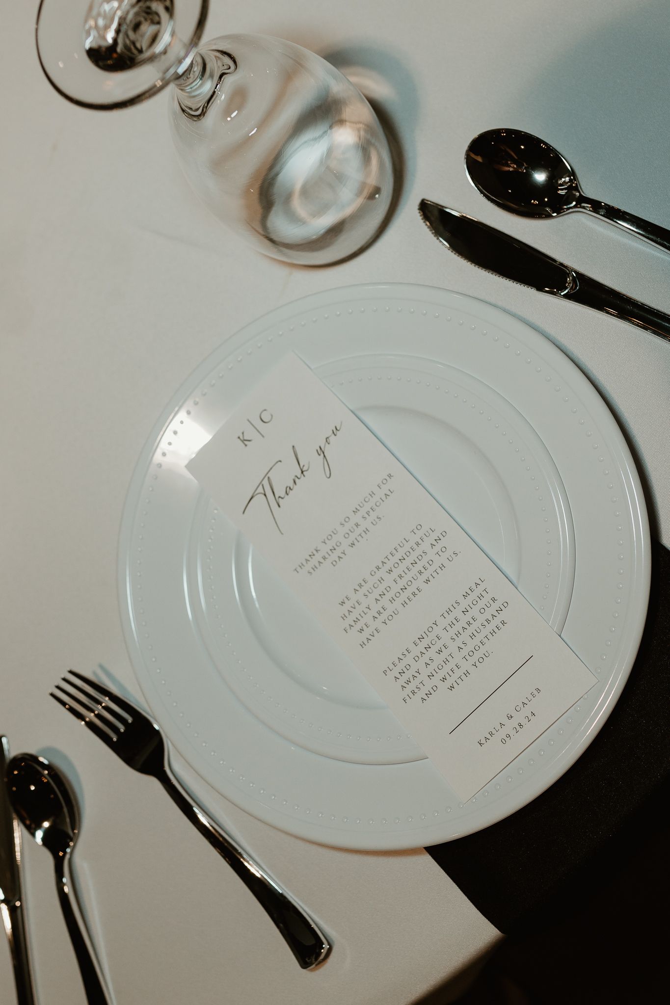 Place settings with white plates and printed menus at an elegant wedding reception.