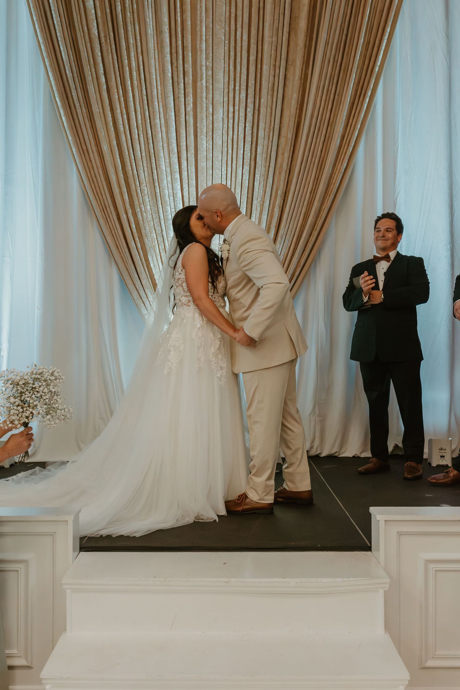 Wedding ceremony moment on stage with elegant draped backdrop.