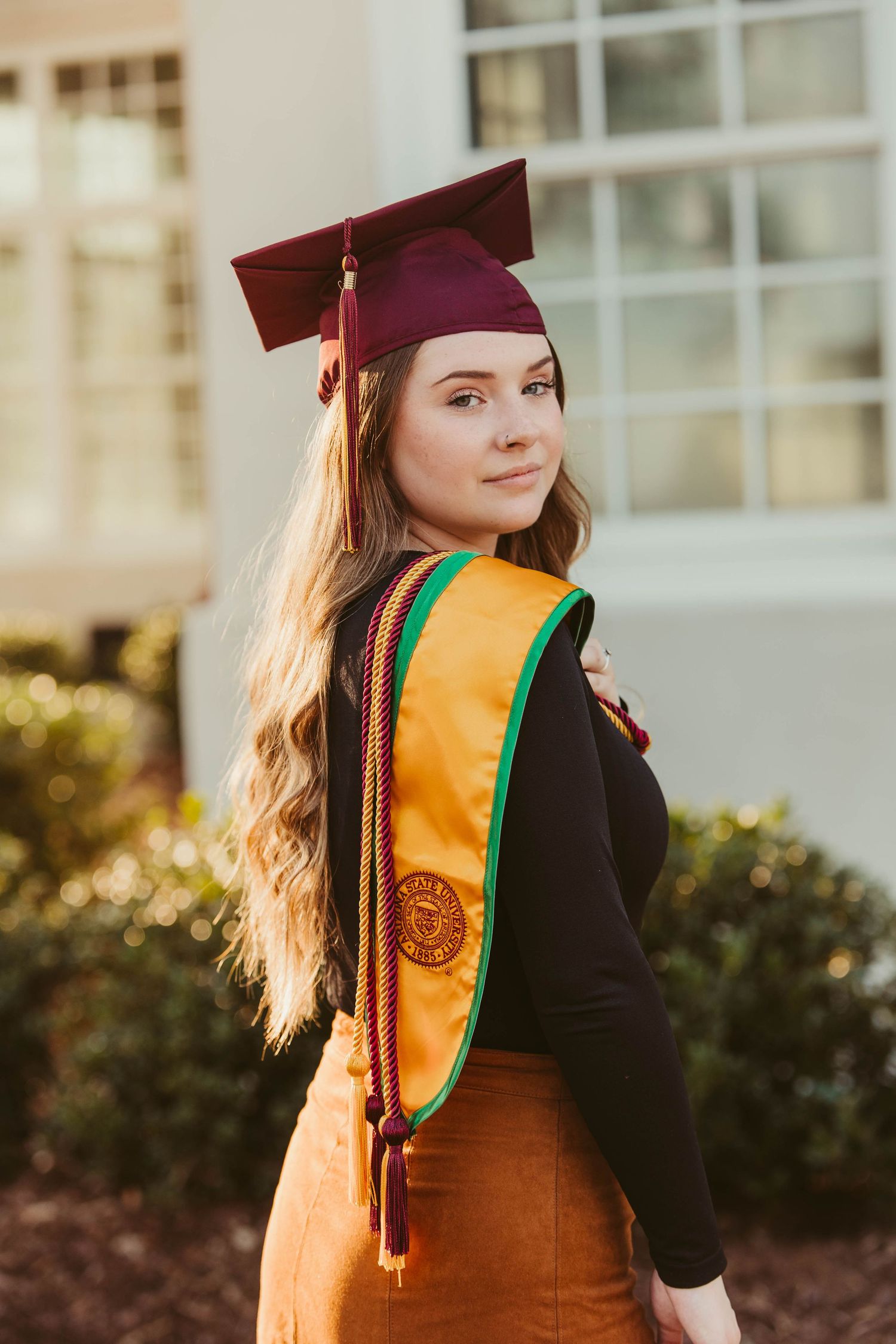 Graduation portraits showing academic regalia with burgundy cap and gold sash against white columns.