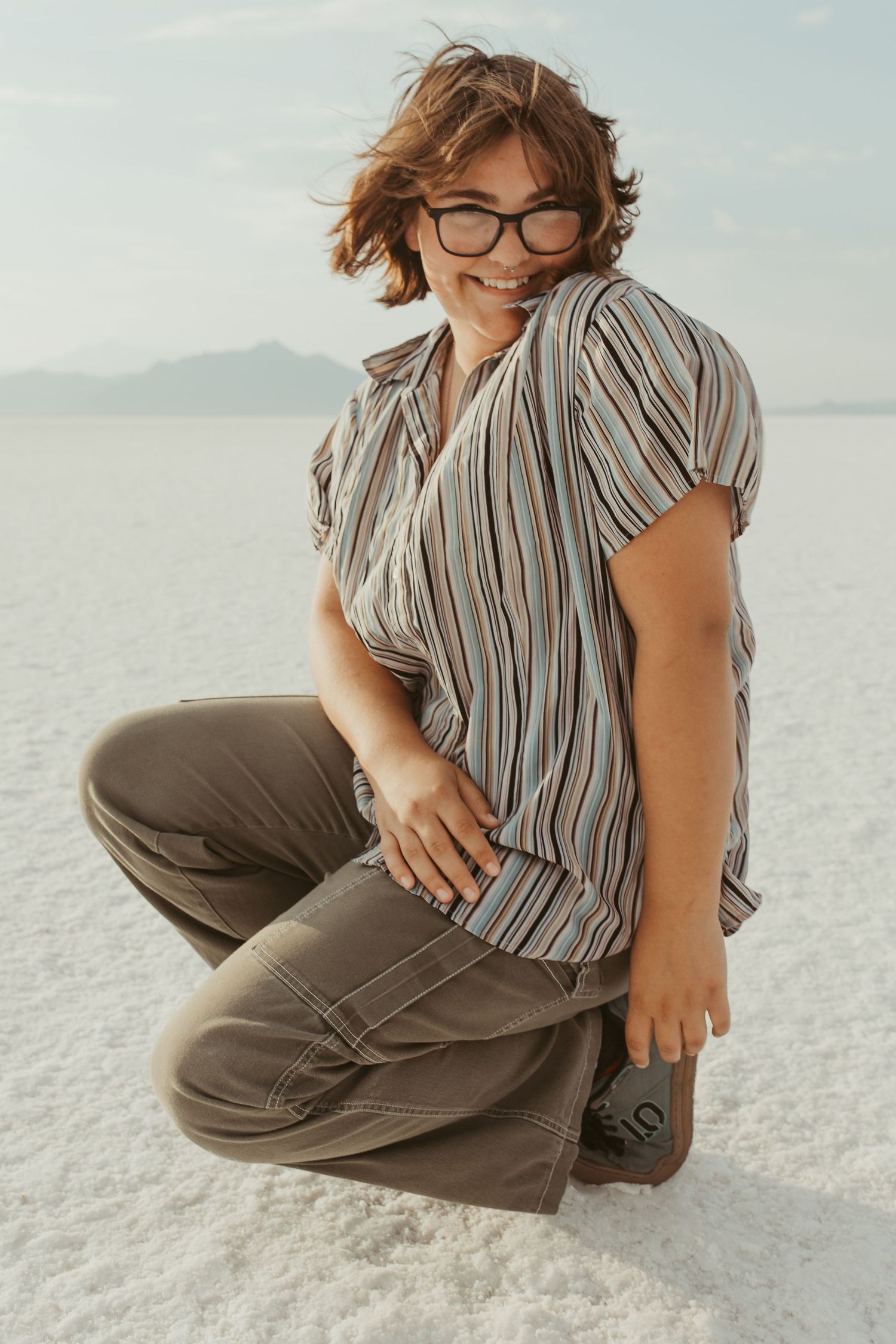 Casual portraits on salt flats wearing striped shirt and olive pants.