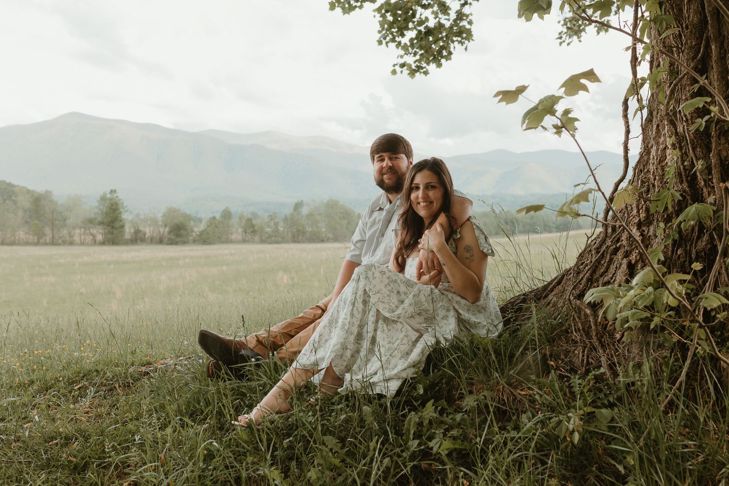 Romantic countryside photoshoot with rolling hills and large trees in the background.