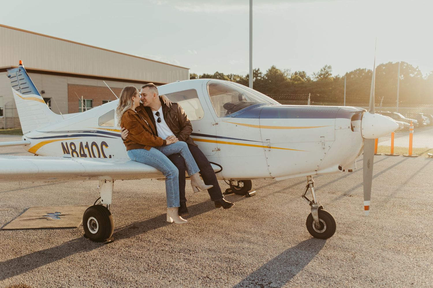 Small private aircraft parked on gravel runway at sunset.