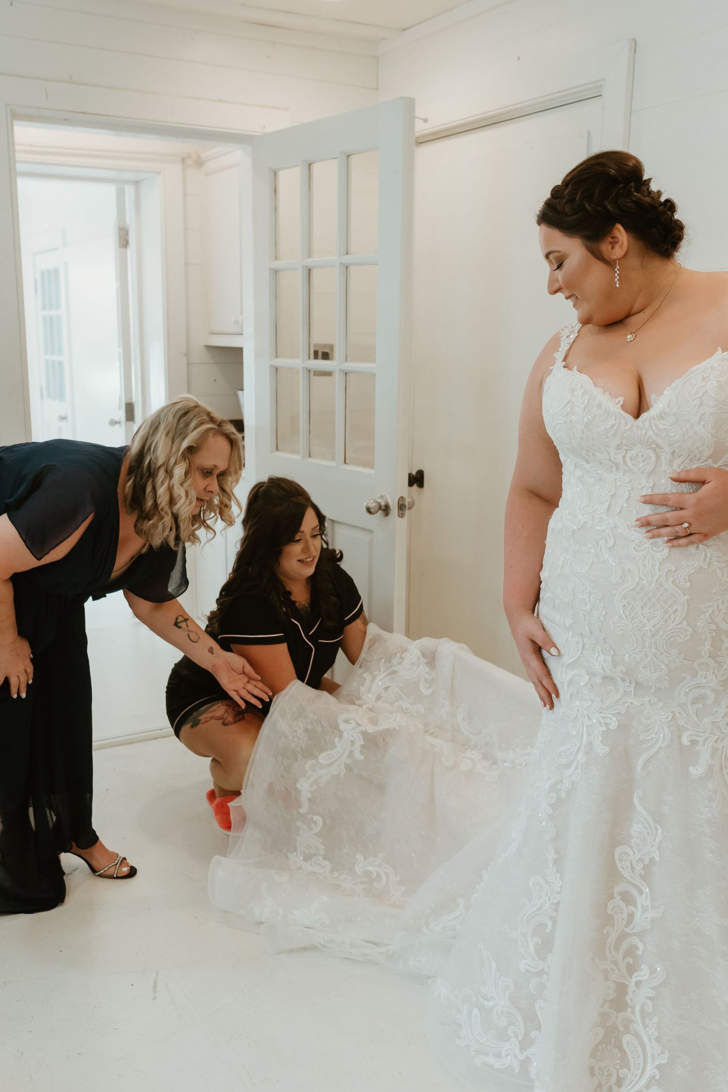 Wedding dress fitting session with attendants helping adjust the gown.