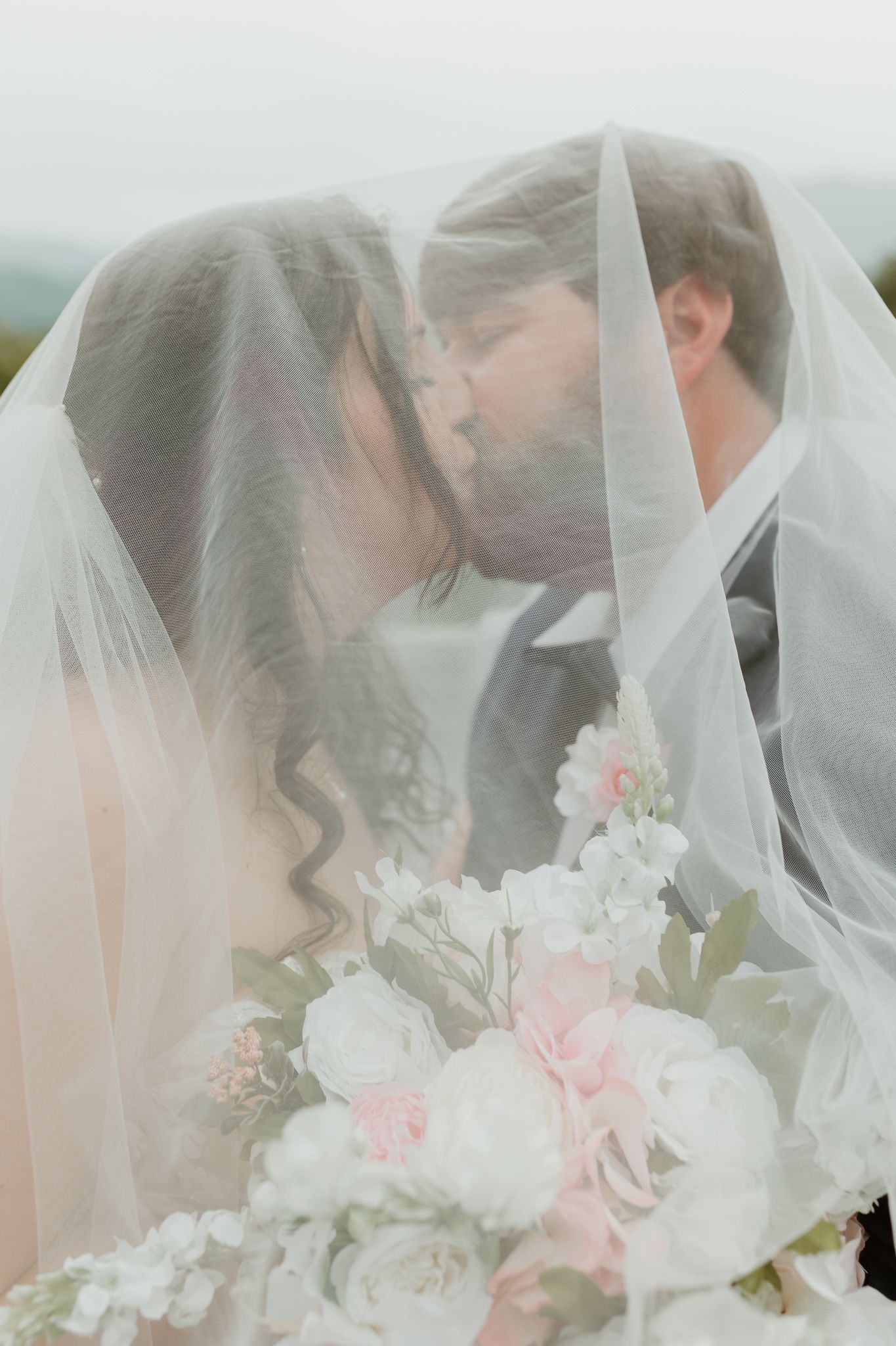 Close-up of bridal veil with delicate pink and white floral bouquet.