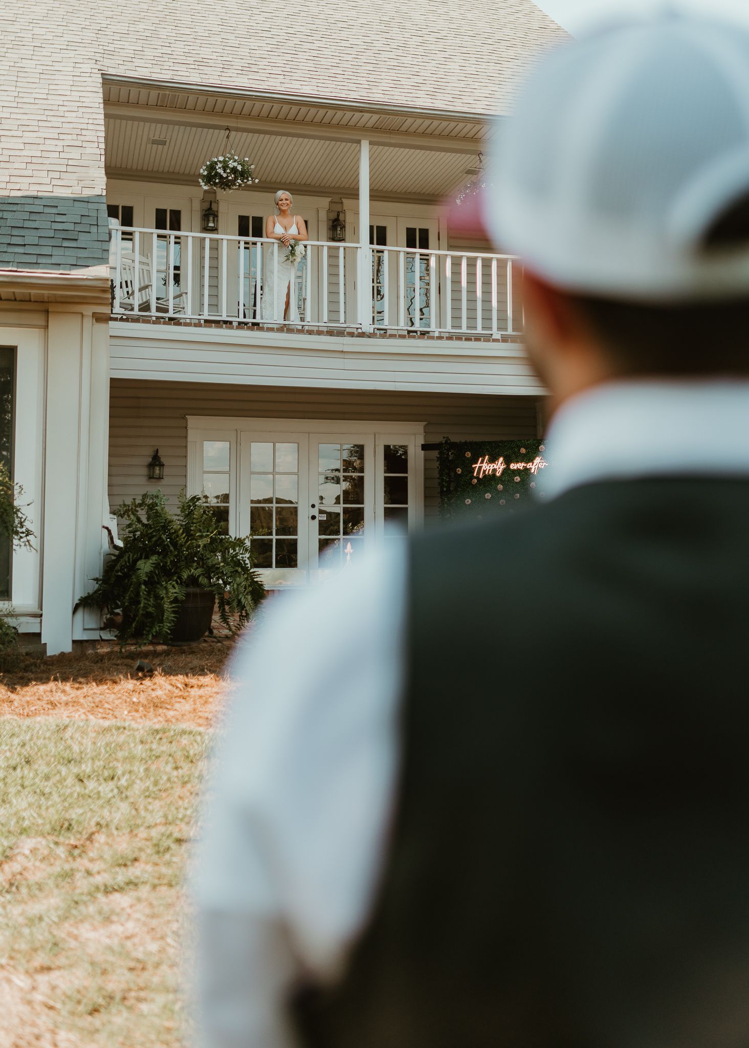 Distant view of a white colonial-style house with a wraparound porch.