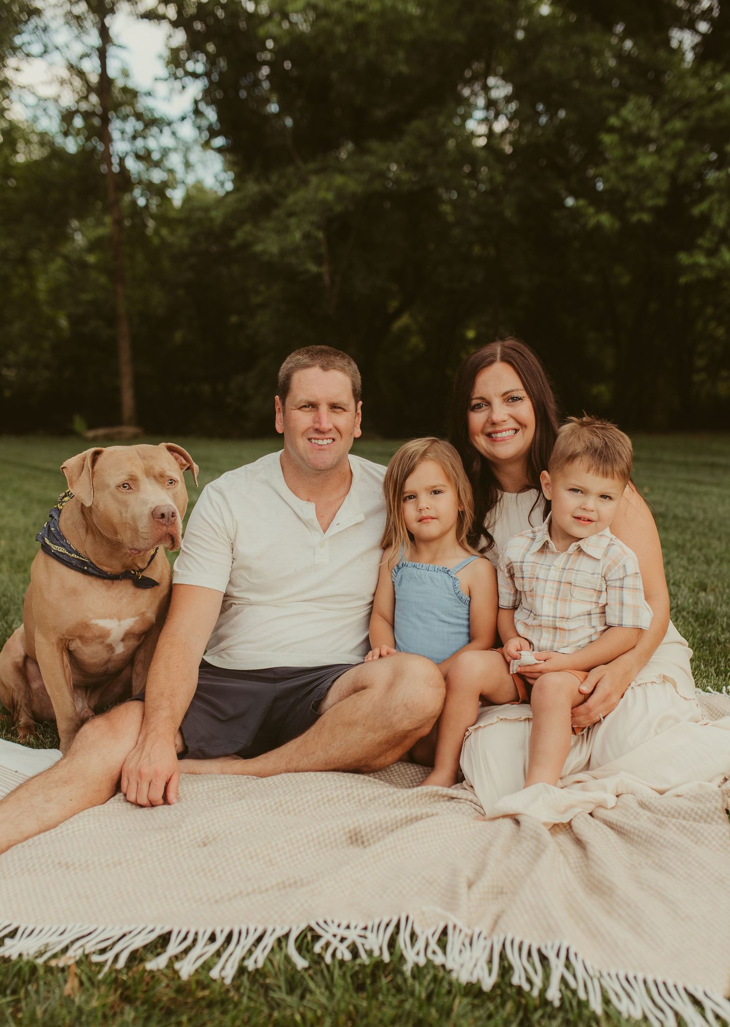 A family and their dog relax together on a white blanket during an outdoor photo session Chattanooga Family Photographer