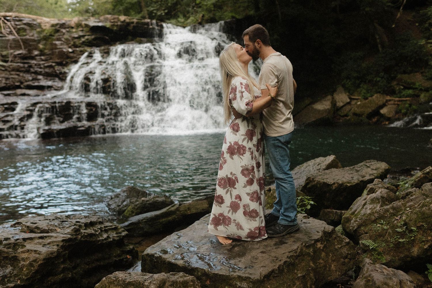 A romantic waterfall engagement photo session showing tender moments between a couple in nature.