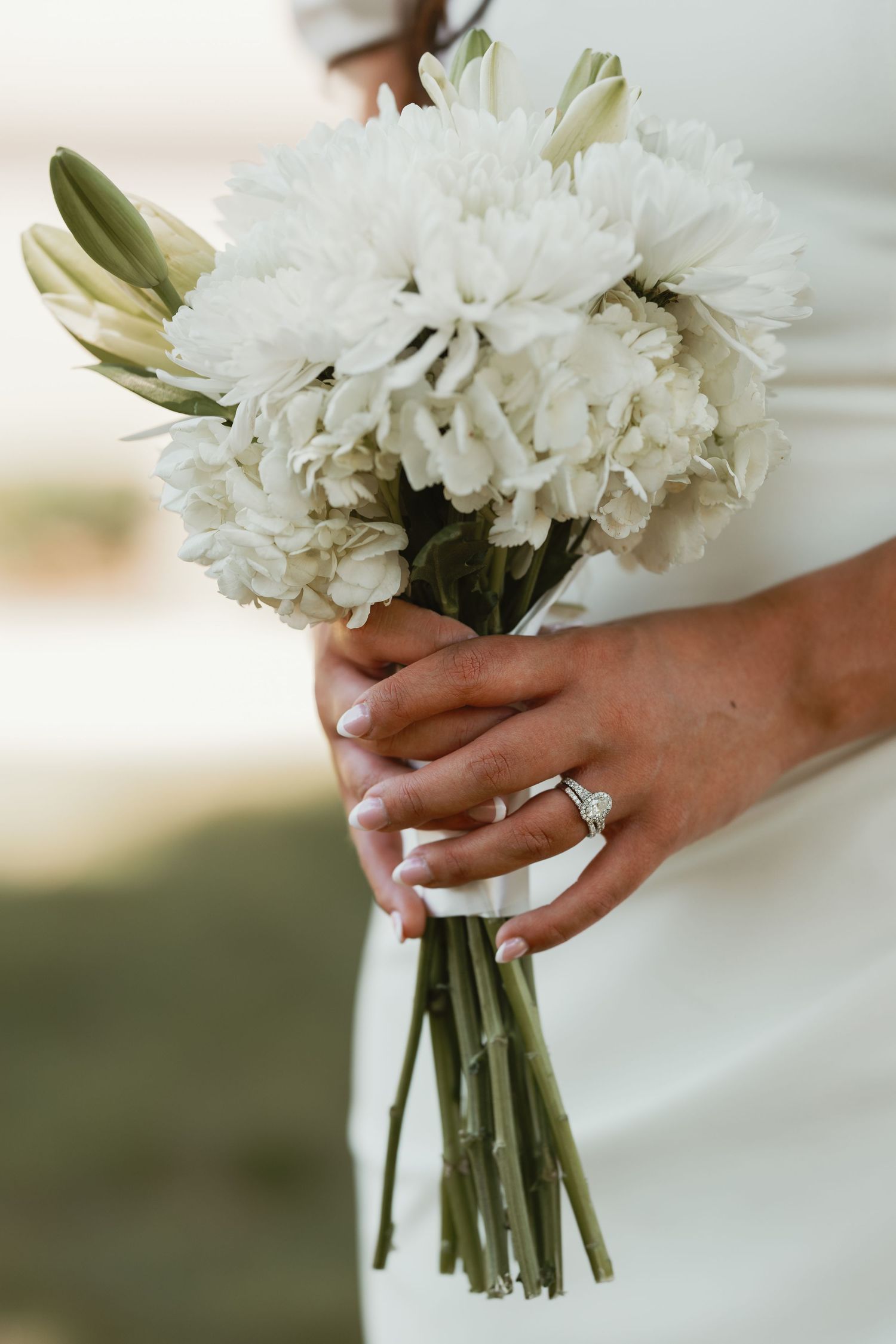 Close-up of white floral wedding bouquet with green stems being held.