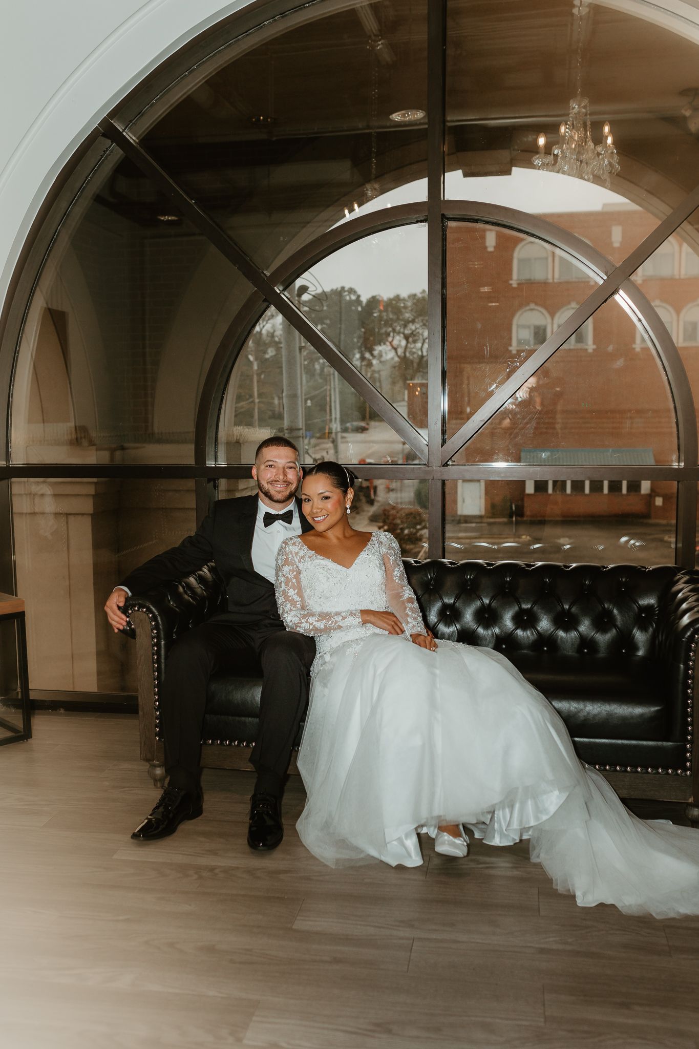 Wedding couple relaxing on a leather couch in an elegant venue.