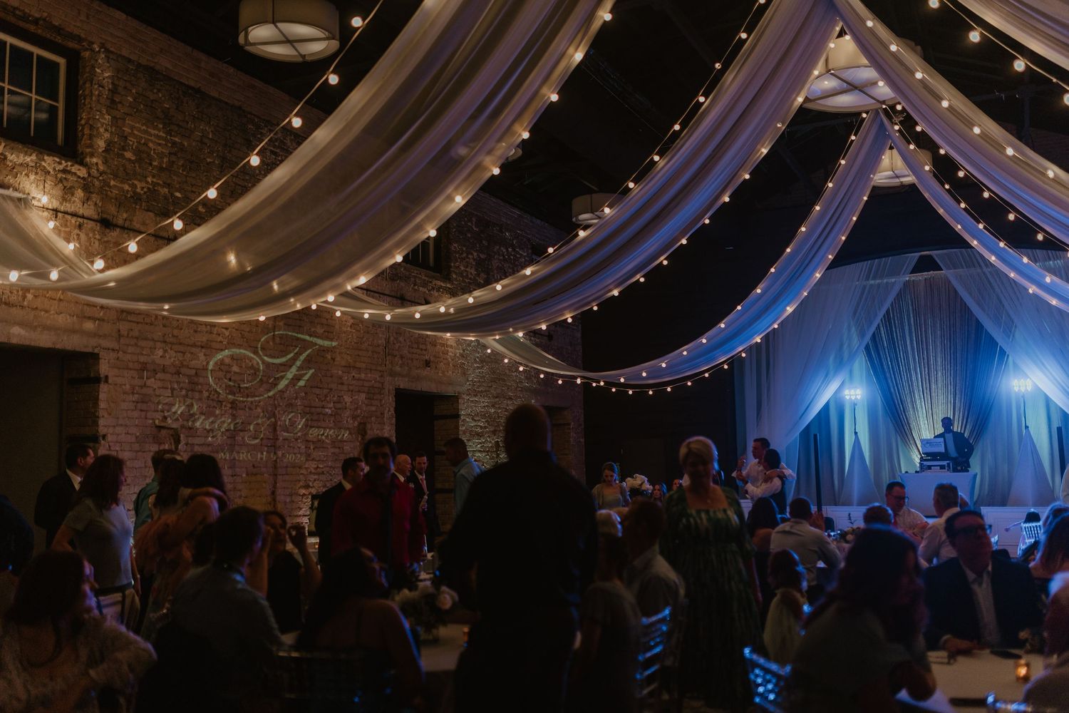 Wedding reception venue with draped fabric ceiling and string lights creating romantic ambiance.