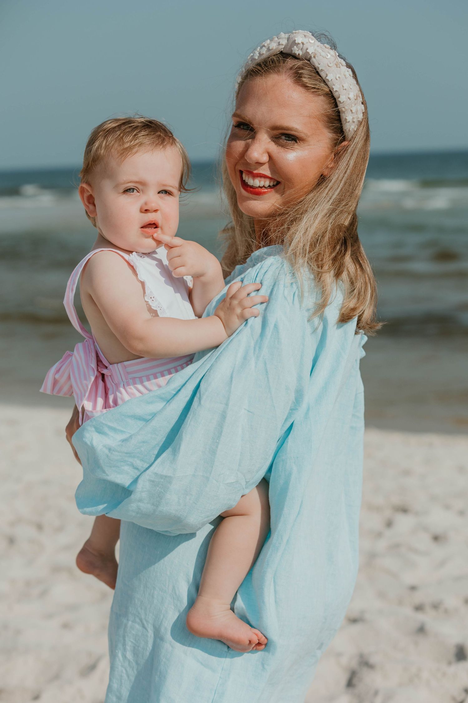 A light blue dress flows in the ocean breeze during a beach photoshoot.