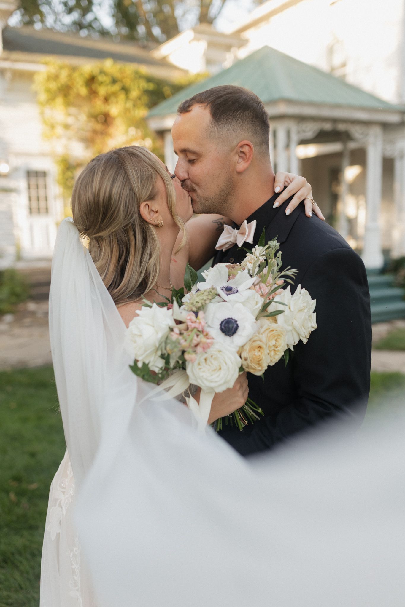 Romantic wedding kiss with white and peach floral bouquet in garden setting.Chattanooga Wedding Photographer