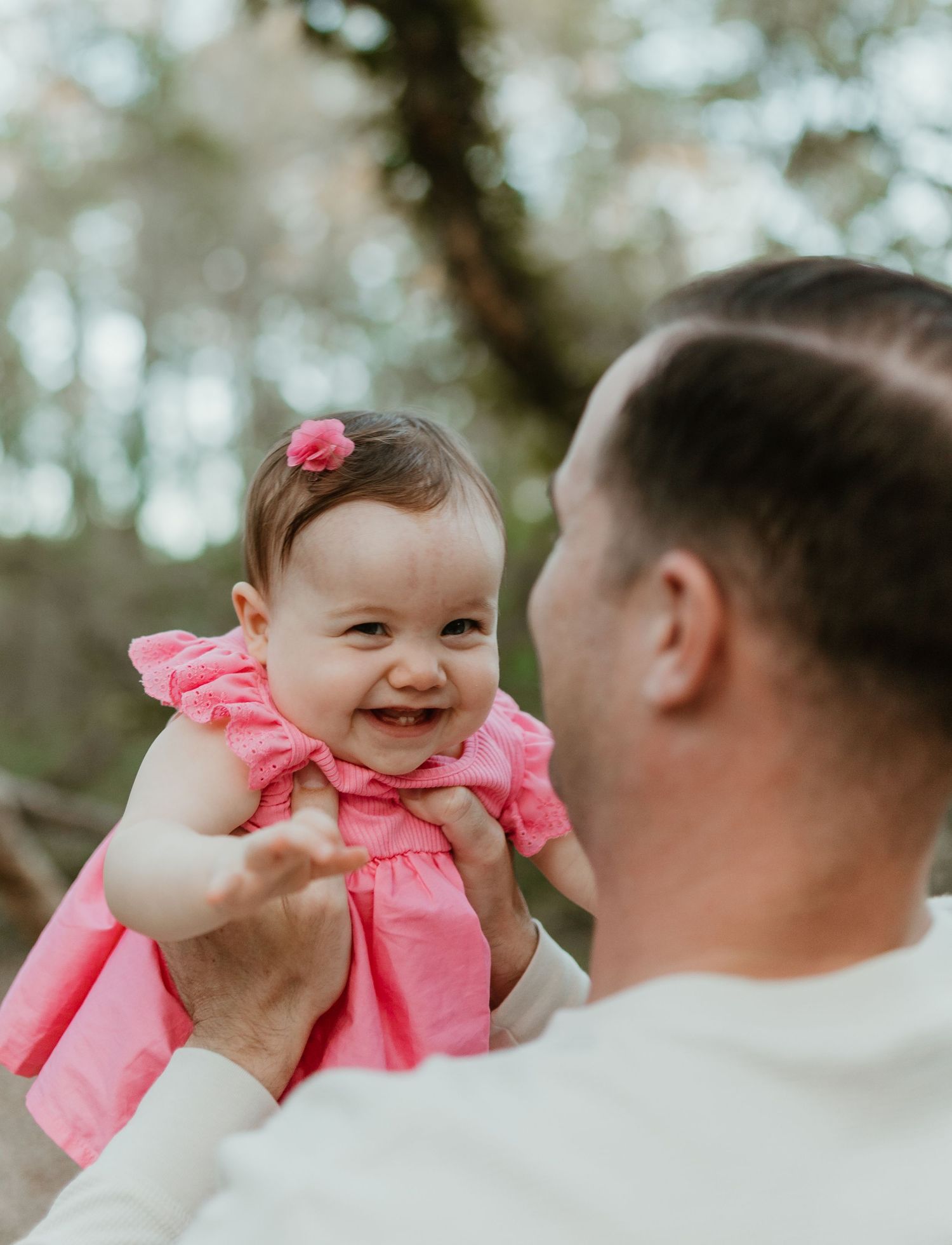 A heartwarming moment of laughter between adult and baby in pink ruffled dress.