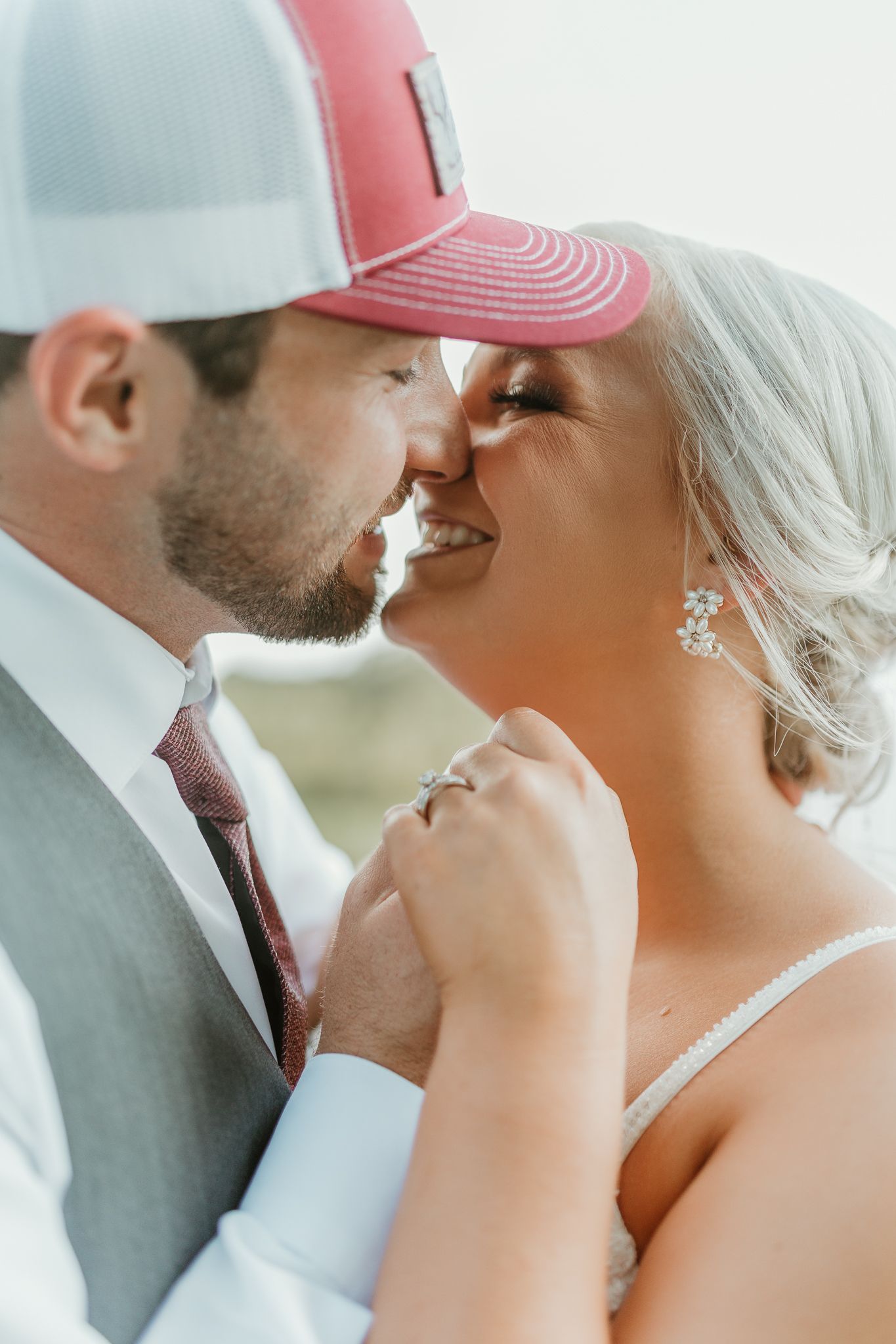 Close-up series of tender moments between a couple wearing baseball caps on their wedding day.