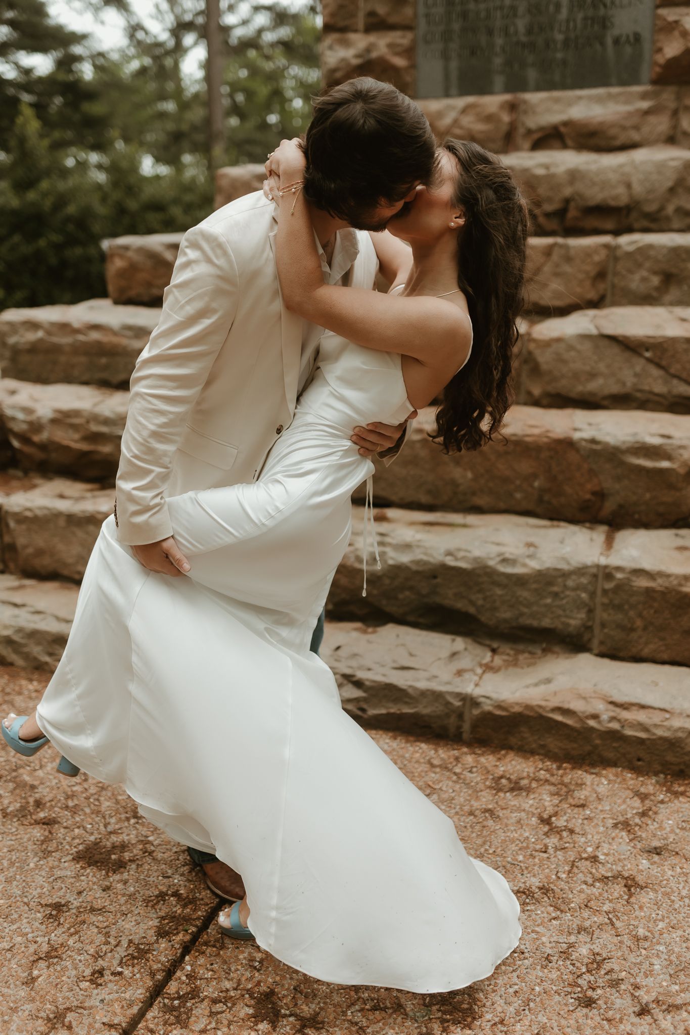 A romantic moment captured on stone steps with a white dress flowing in the breeze.