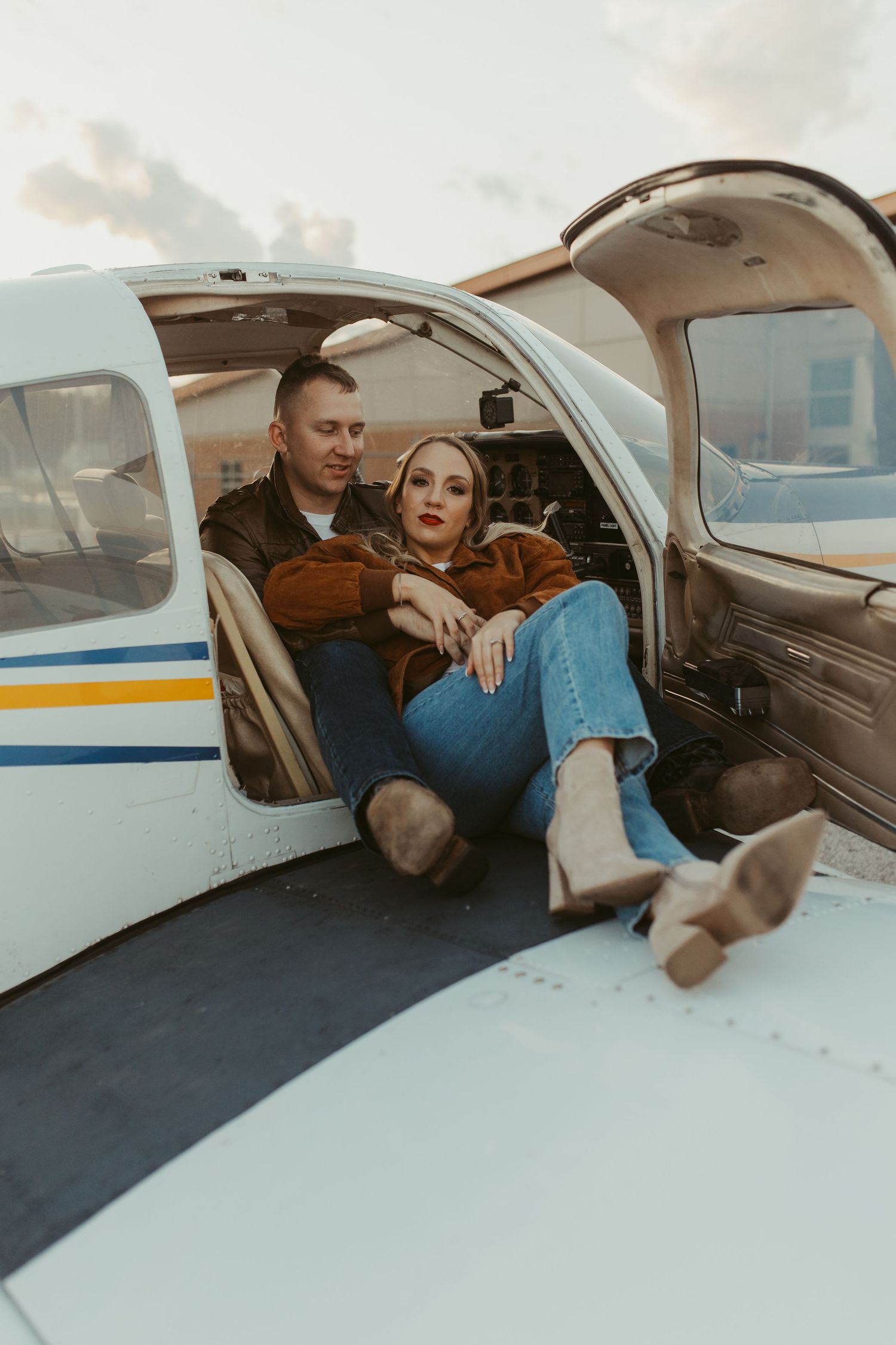 Two people sitting inside a small private aircraft sharing a romantic moment.