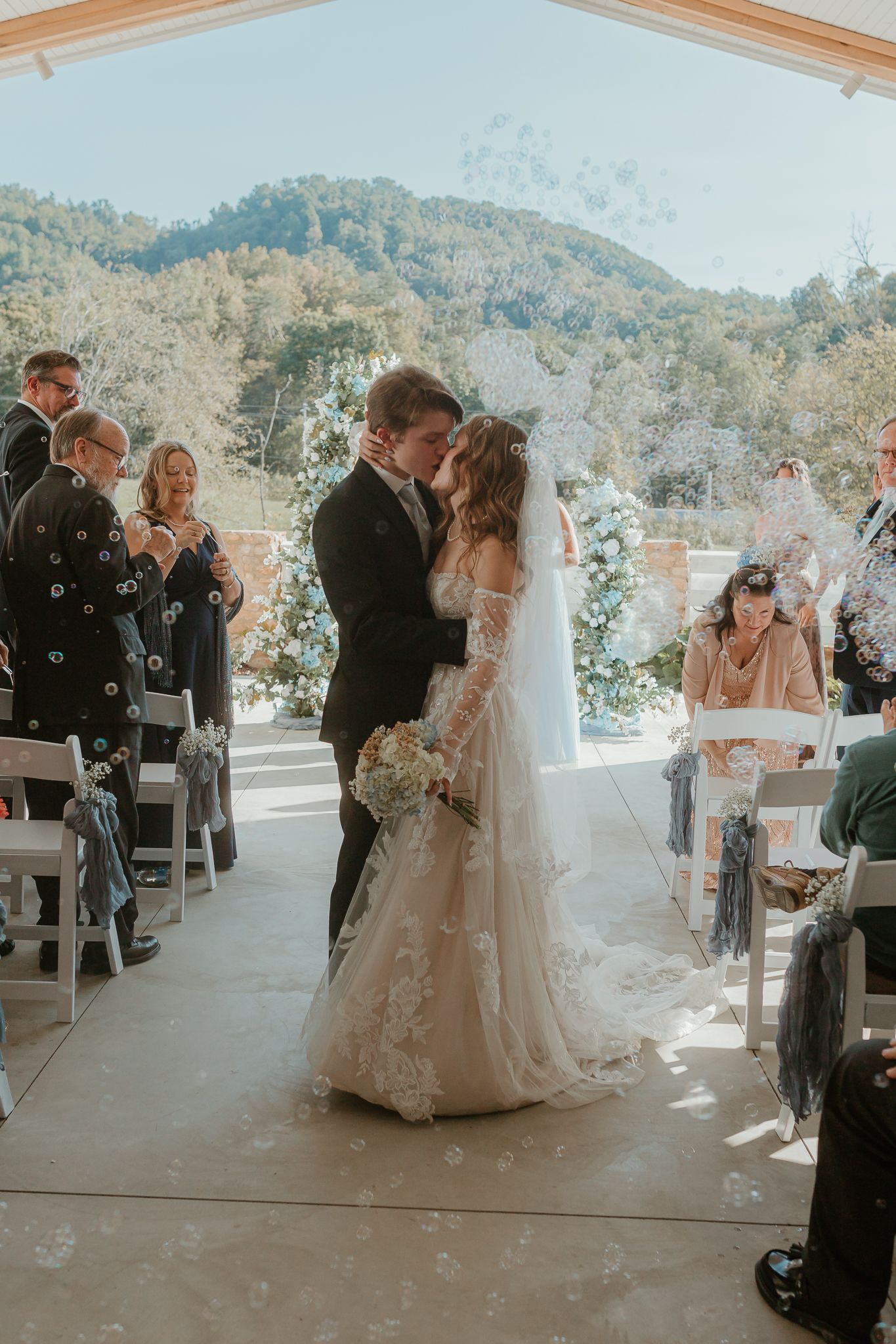 Wedding ceremony recessional with guests throwing confetti in outdoor pavilion.